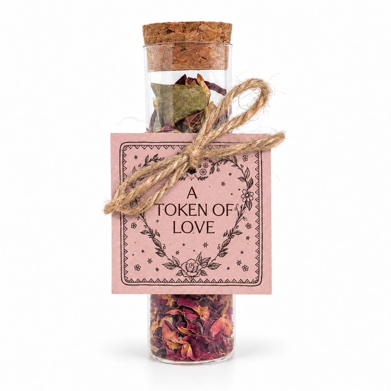 A Token of Love intention vial filled with dried botanicals and finished with a cork, twine bow and hand-tied pink heart tag.