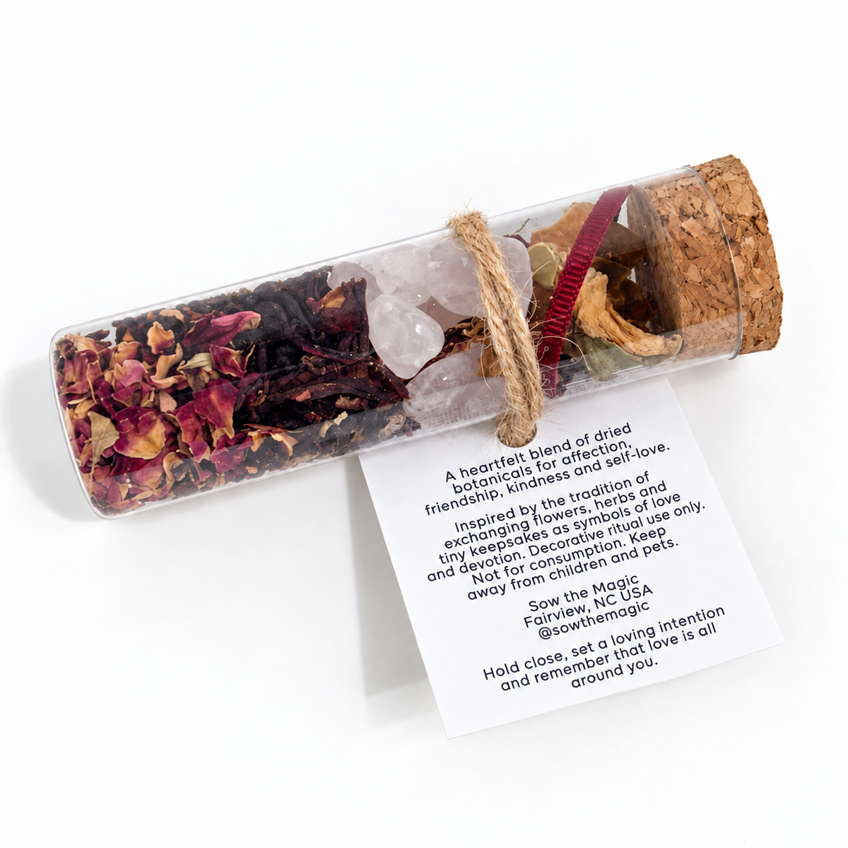 A Token of Love botanical intention vial shown horizontally with the product information and ritual instructions visible on the back tag.