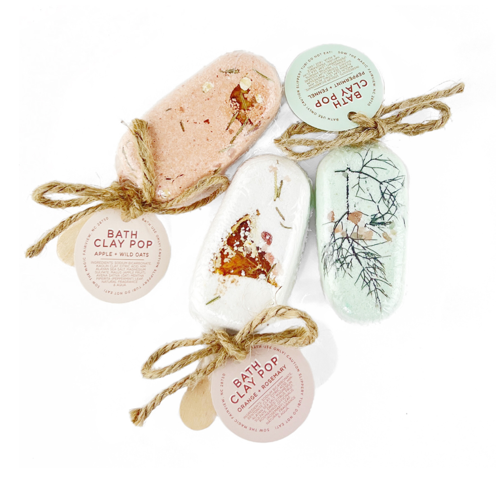 Three bath clay pop bars tied with twine, pastel colors on white background