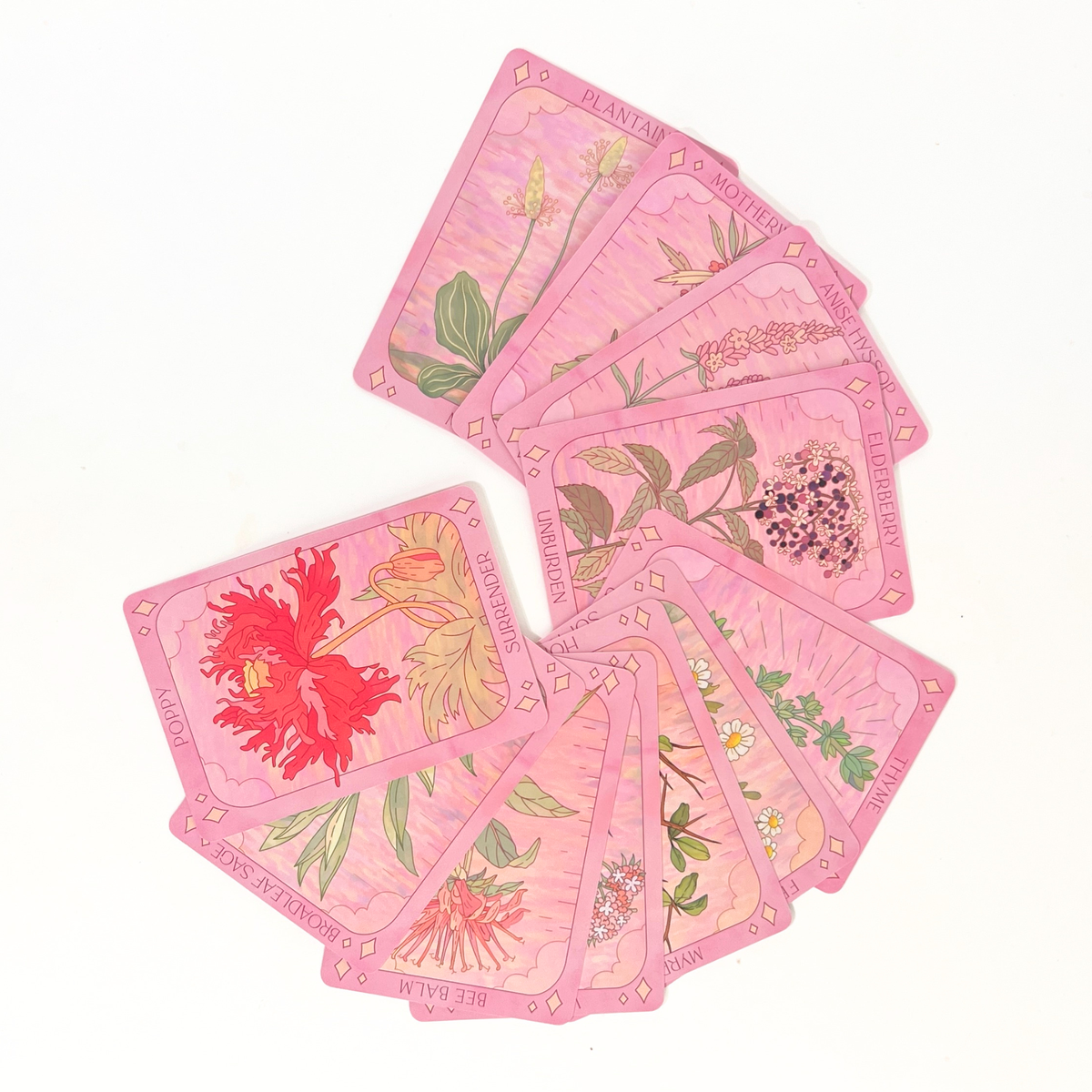 Sow the Magic Plant Guardians Oracle cards arranged in a fan, featuring pink botanical illustrations of flowers and medicinal herbs.