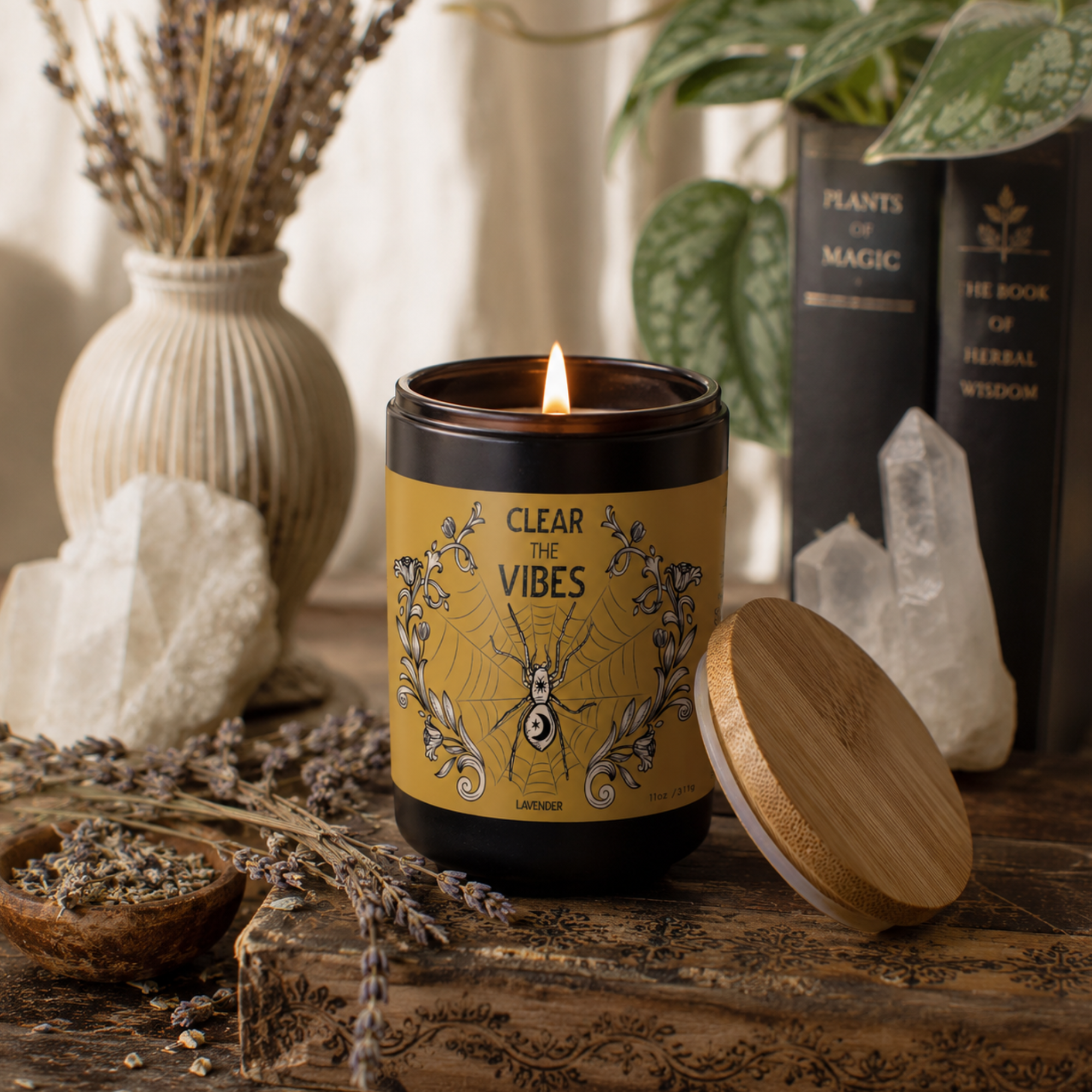 Lit Clear the Vibes Lavender candle by Sow the Magic displayed in a cozy botanical setting with dried lavender, clear quartz crystals, vintage-inspired books and natural wood accents. The black glass candle with a bamboo lid creates a calming home décor scene perfect for relaxation, meditation and aromatherapy.