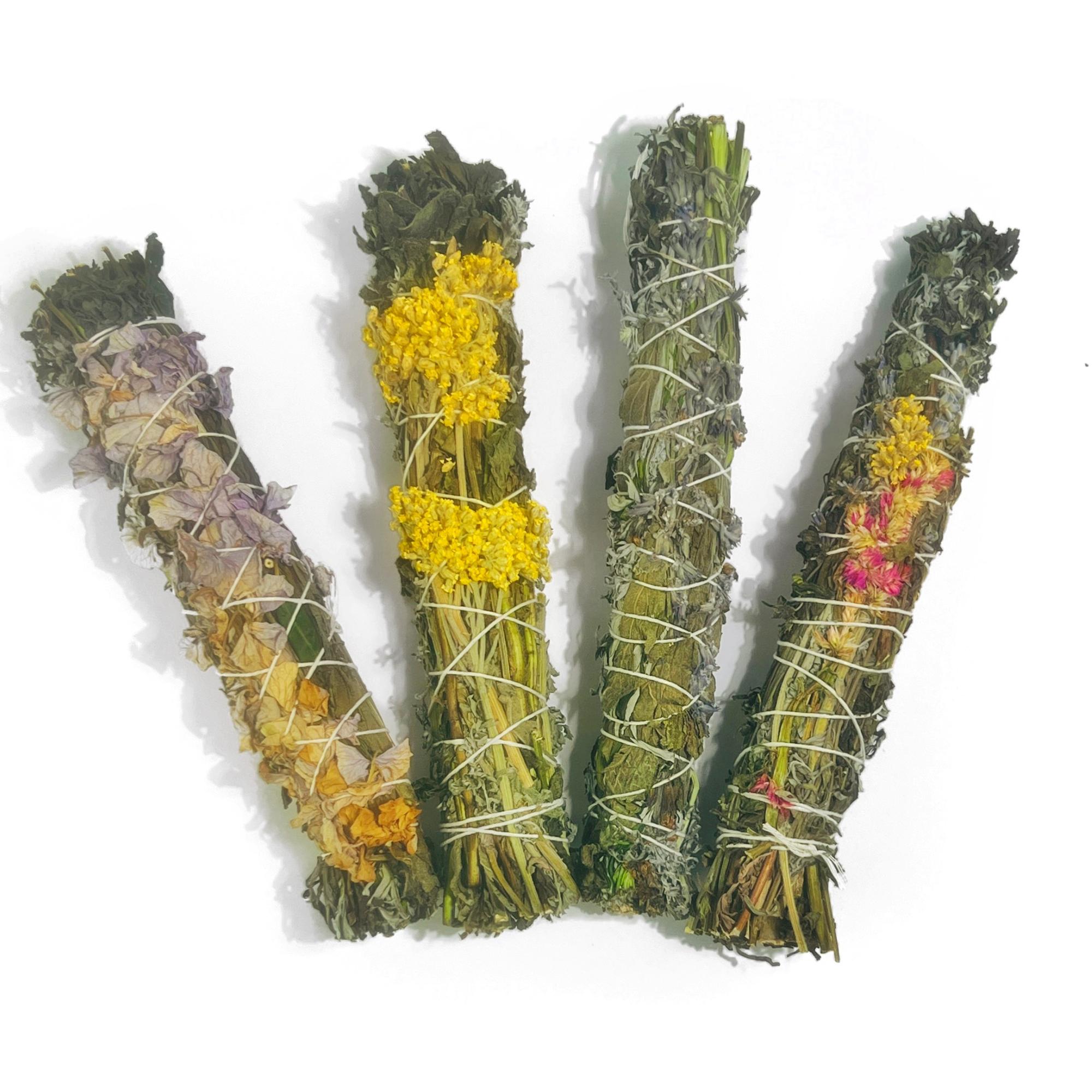 Four dried herb smudge sticks wafting wands with lavender, yellow, and pink flowers, tied with twine
