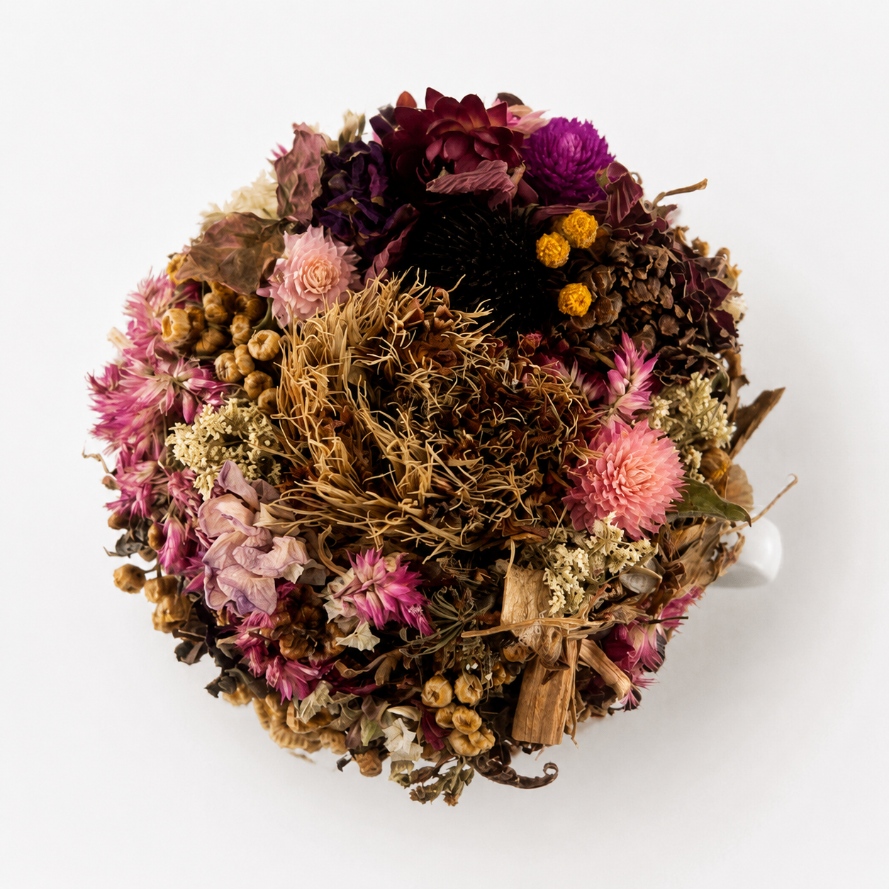 Overhead view of February dried flower teacup arrangement with pink, burgundy and woodland botanical textures