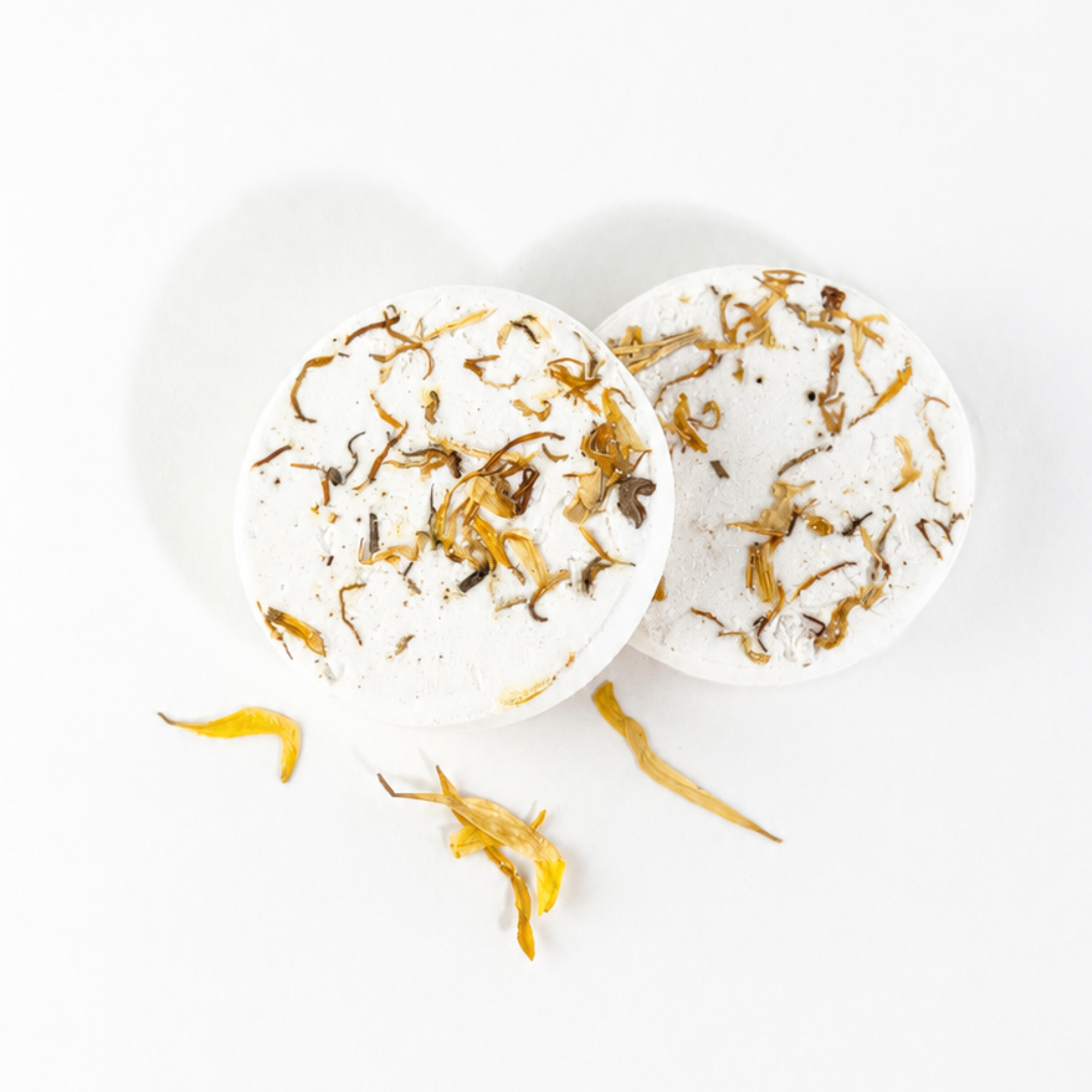 Two handcrafted Frankincense & Myrrh shower steamers decorated with dried botanicals and flower petals on a white background.