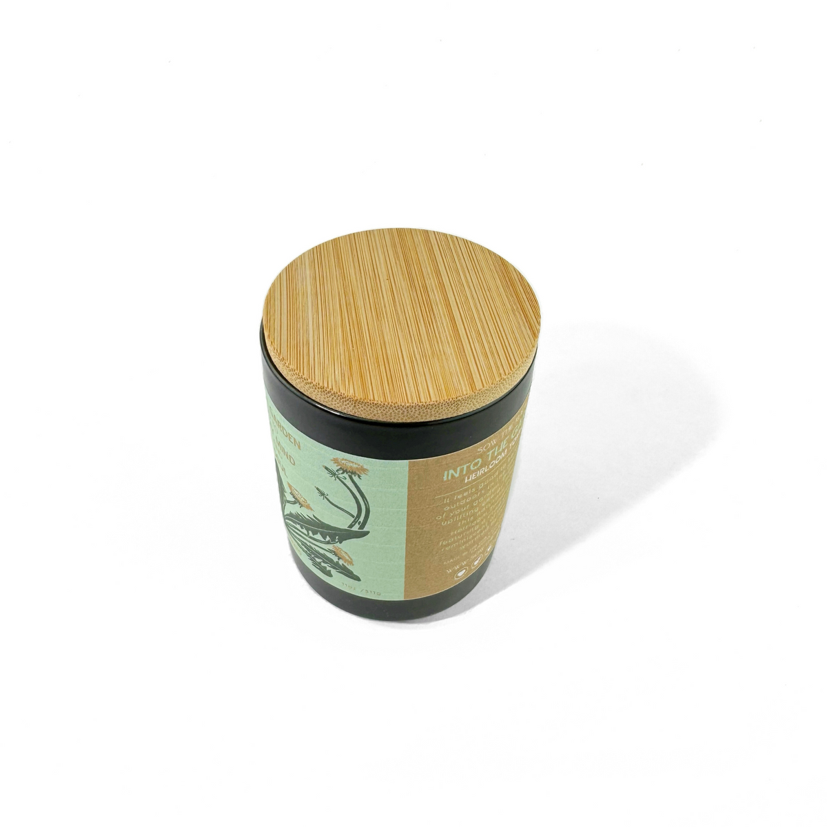 Angled view of the Into the Garden Heirloom Tomato candle with black jar, green label and bamboo lid