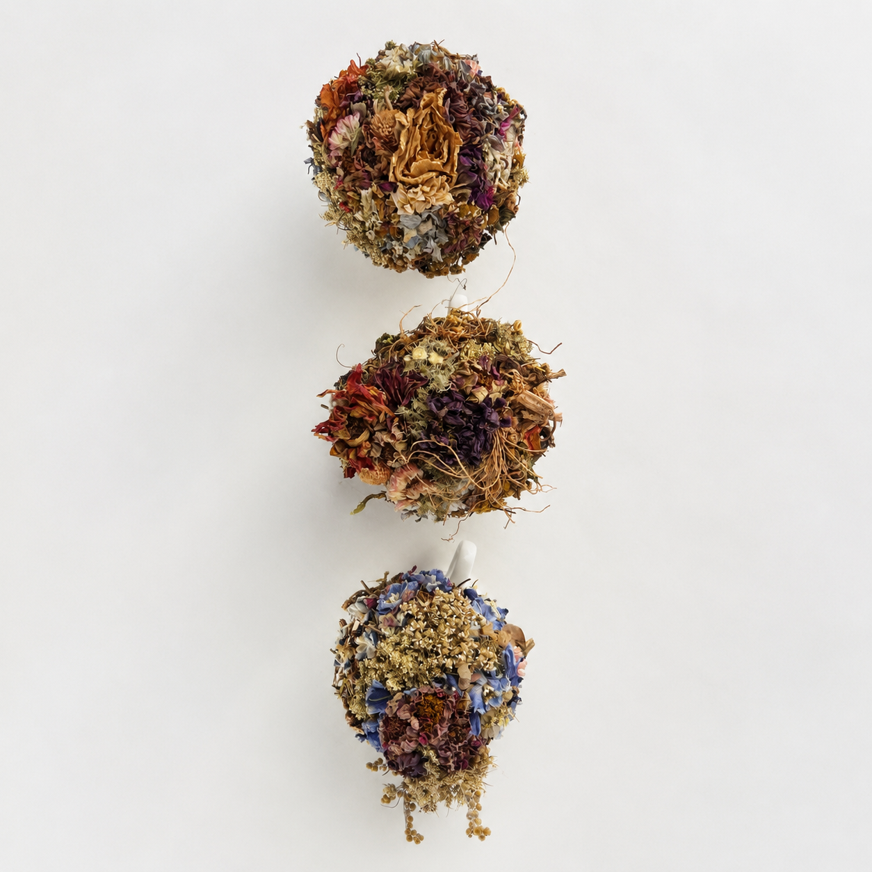 Overhead view showing three one-of-a-kind teacup arrangements with colorful dried flowers and natural textures.