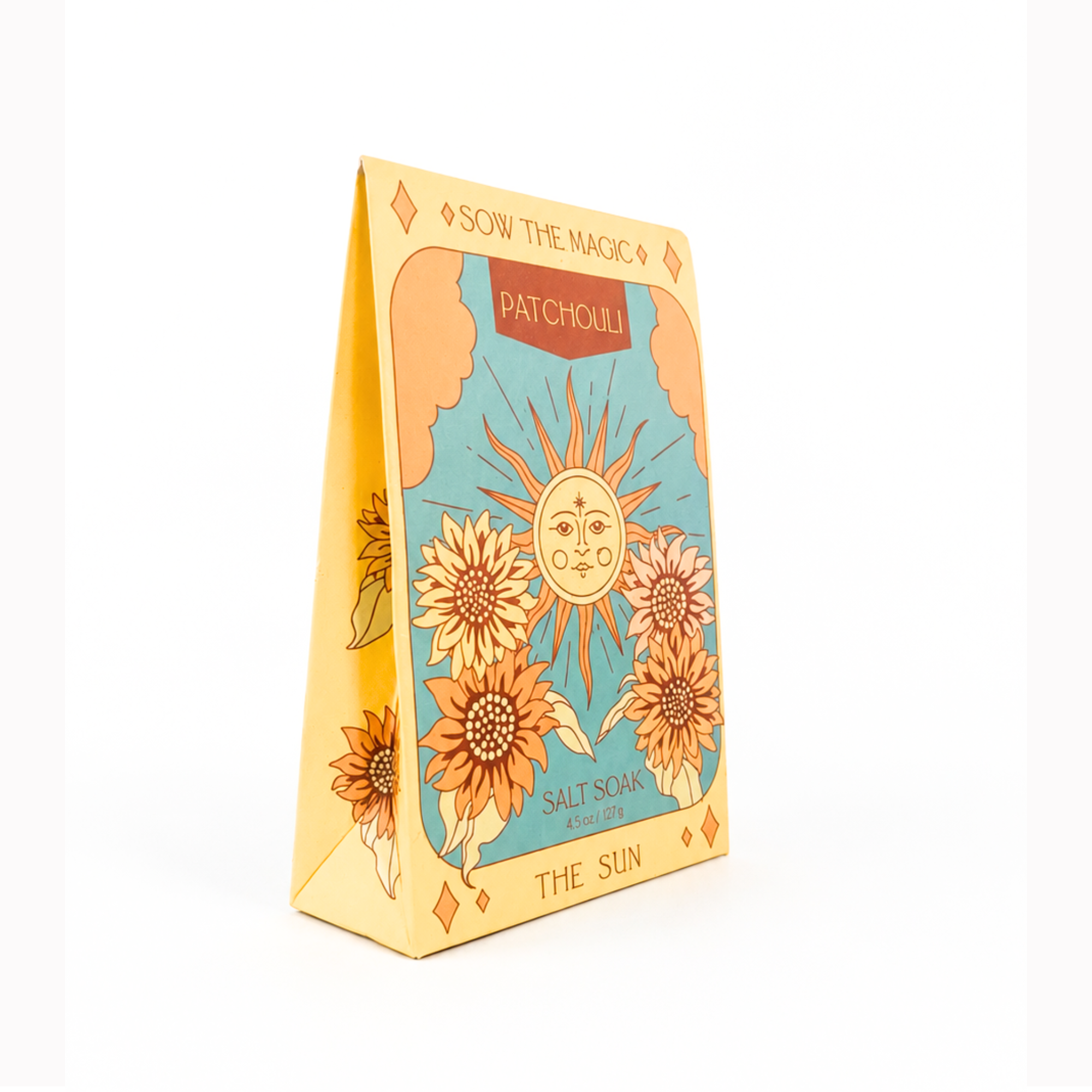 Angled product photo of Sow the Magic® Patchouli Salt Soak – The Sun tarot-inspired botanical bath salts in decorative gift packaging on a bright white background, featuring sunflower artwork for relaxation, self-care and aromatherapy.