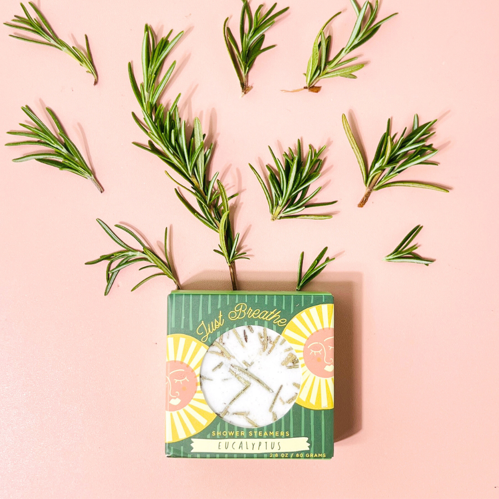 Fresh rosemary sprigs laid over green herb seed packet on pink background