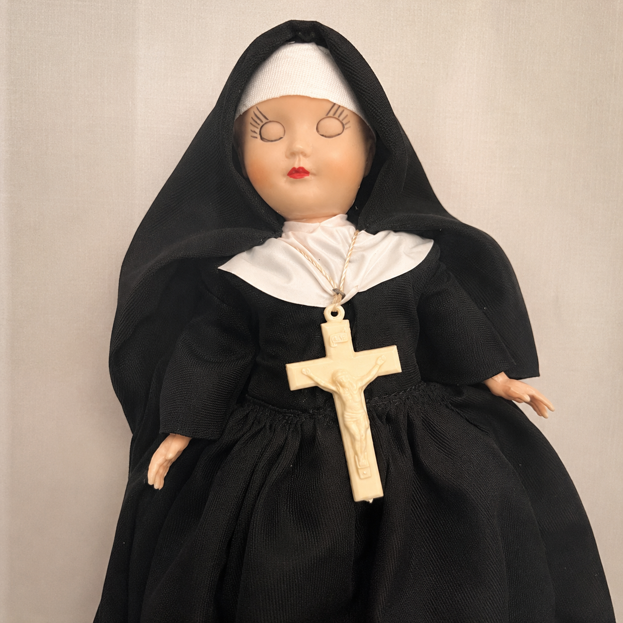 Close-up of Sister, a vintage 1960s sleepy-eye doll wearing a traditional black and white nun habit and cross