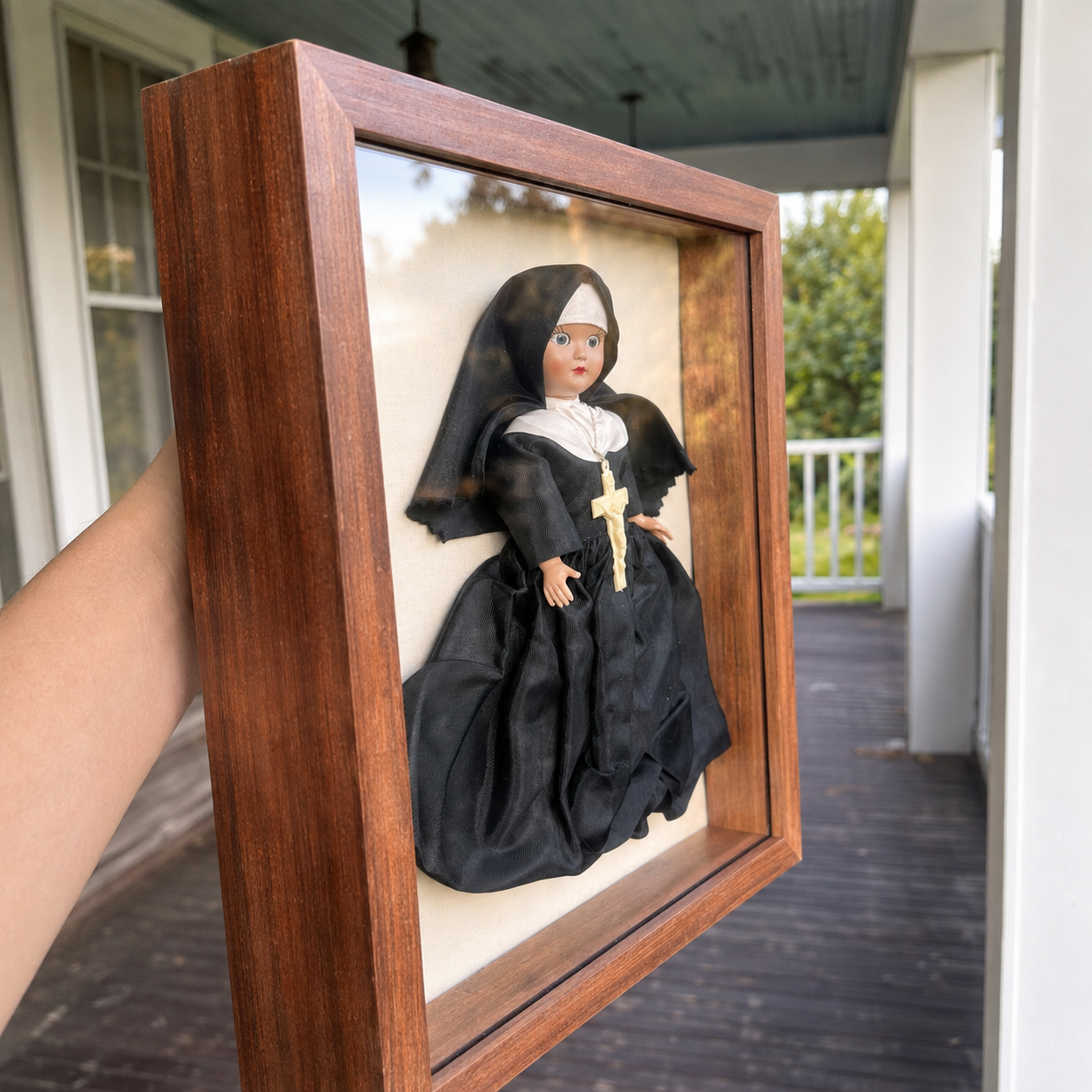 Side view of a framed 1960s vintage sleepy-eye nun doll showing the depth of the wooden shadow box display