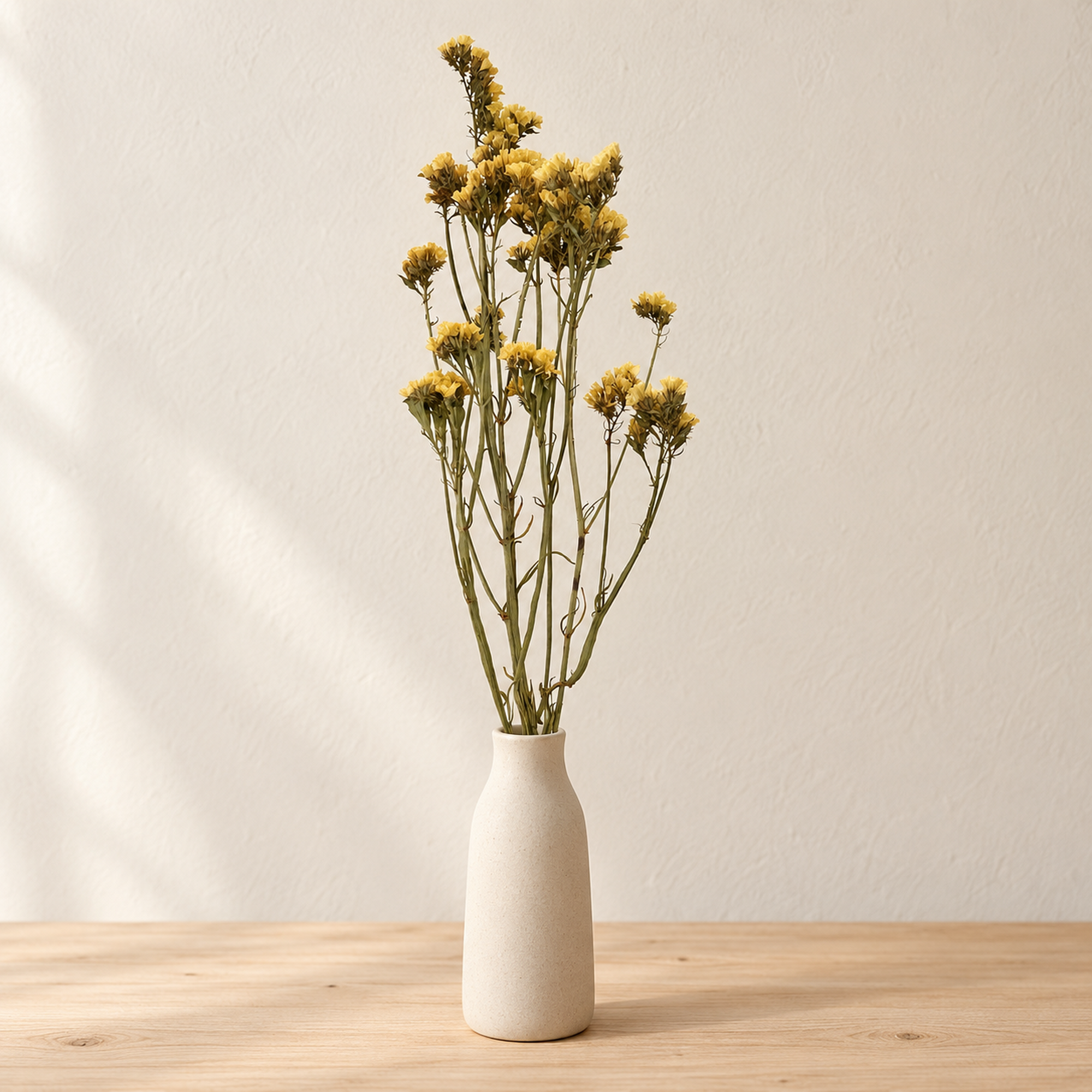 Small bundle of dried yellow statice flowers displayed in a simple white vase