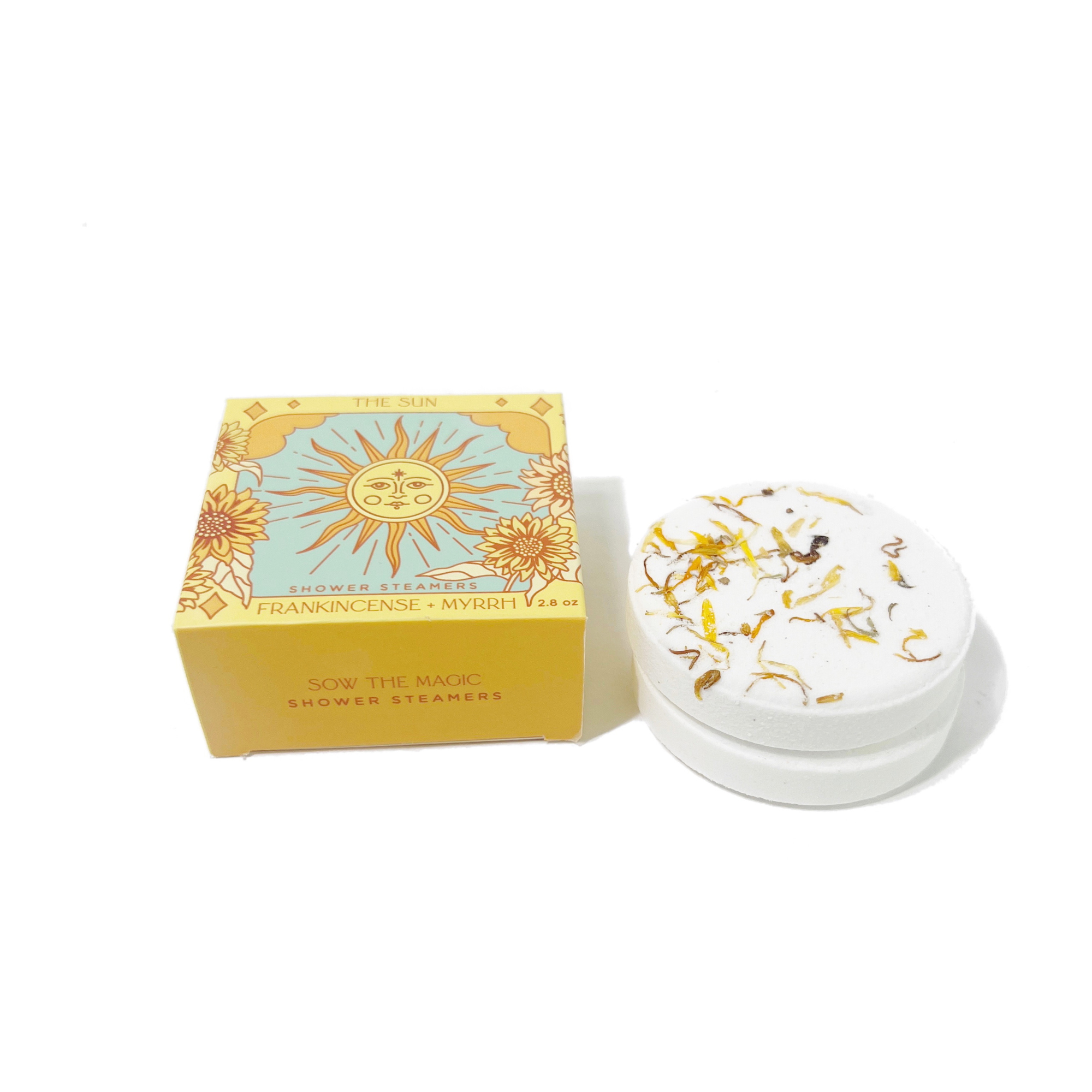 The Sun Shower Steamer Set in Frankincense & Myrrh displayed beside a handcrafted botanical shower steamer.