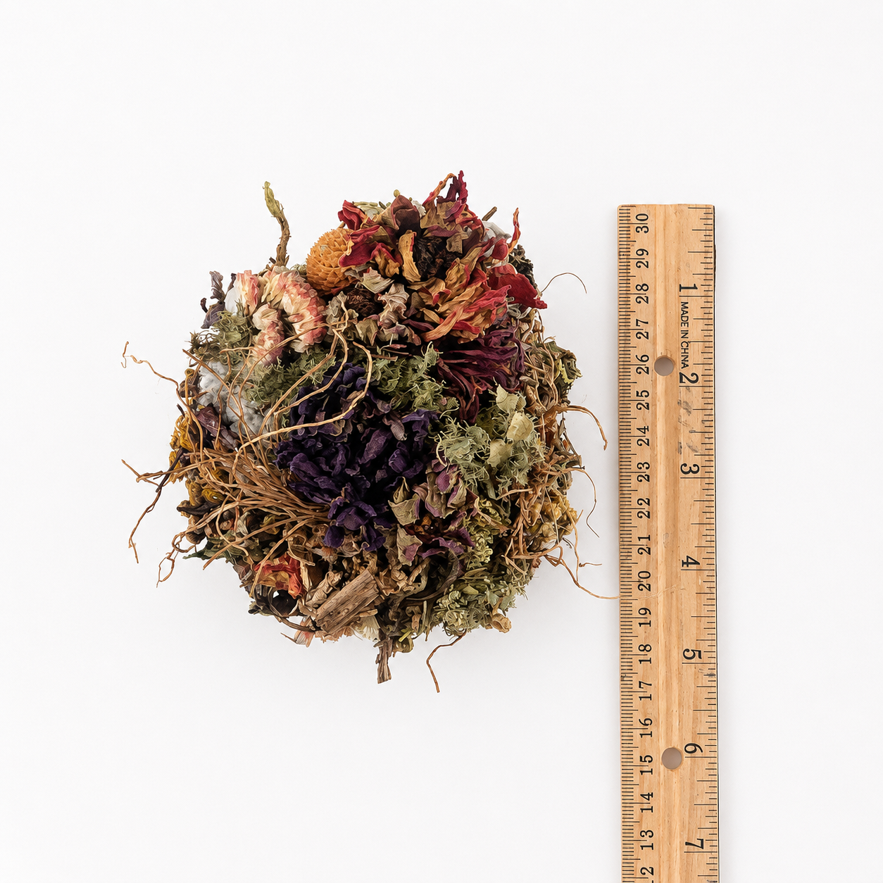 Overhead view of a handmade teacup botanical arrangement beside a ruler for size reference.