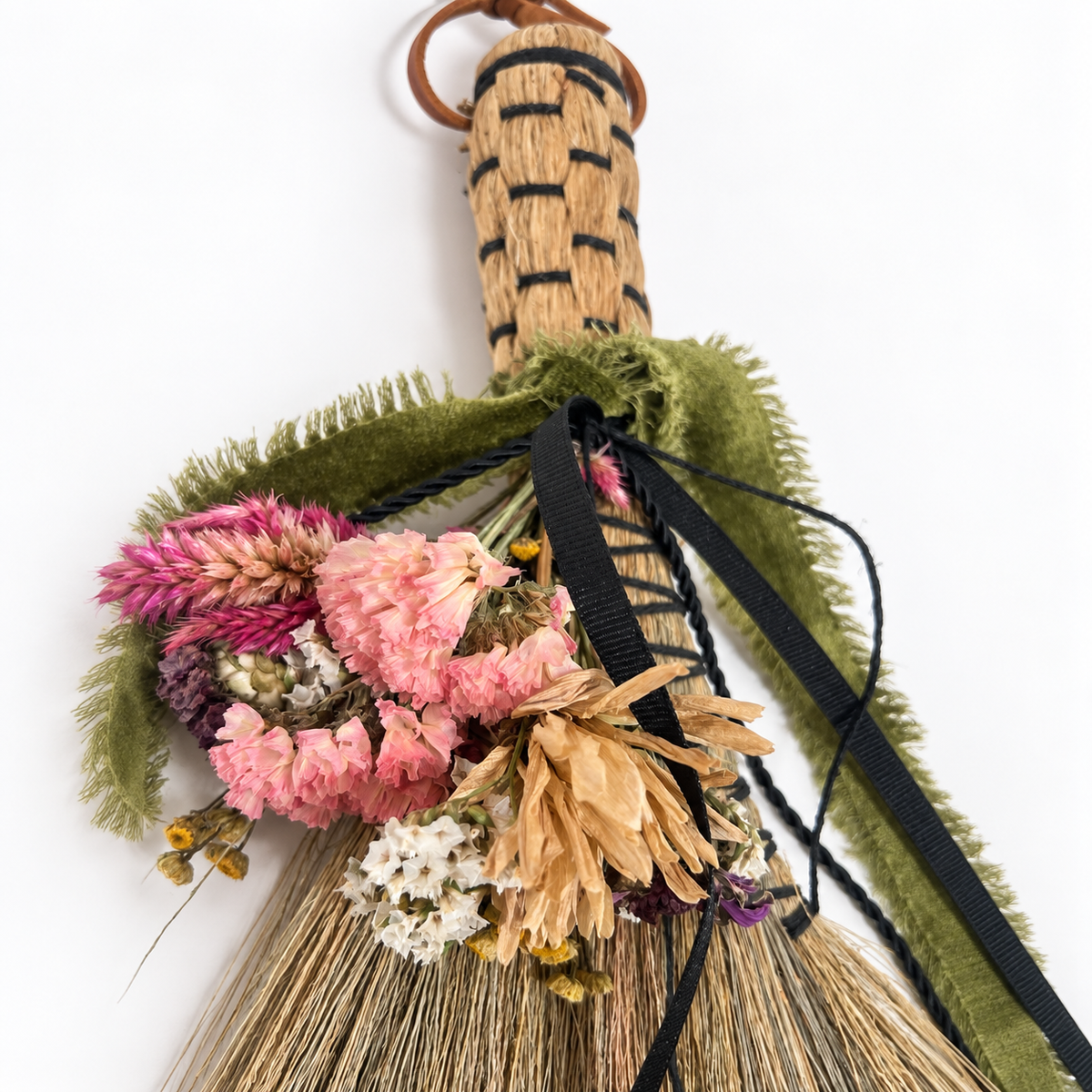 Close-up of dried botanicals, woven handle and ribbon details on the Wildheart Botanical Broom