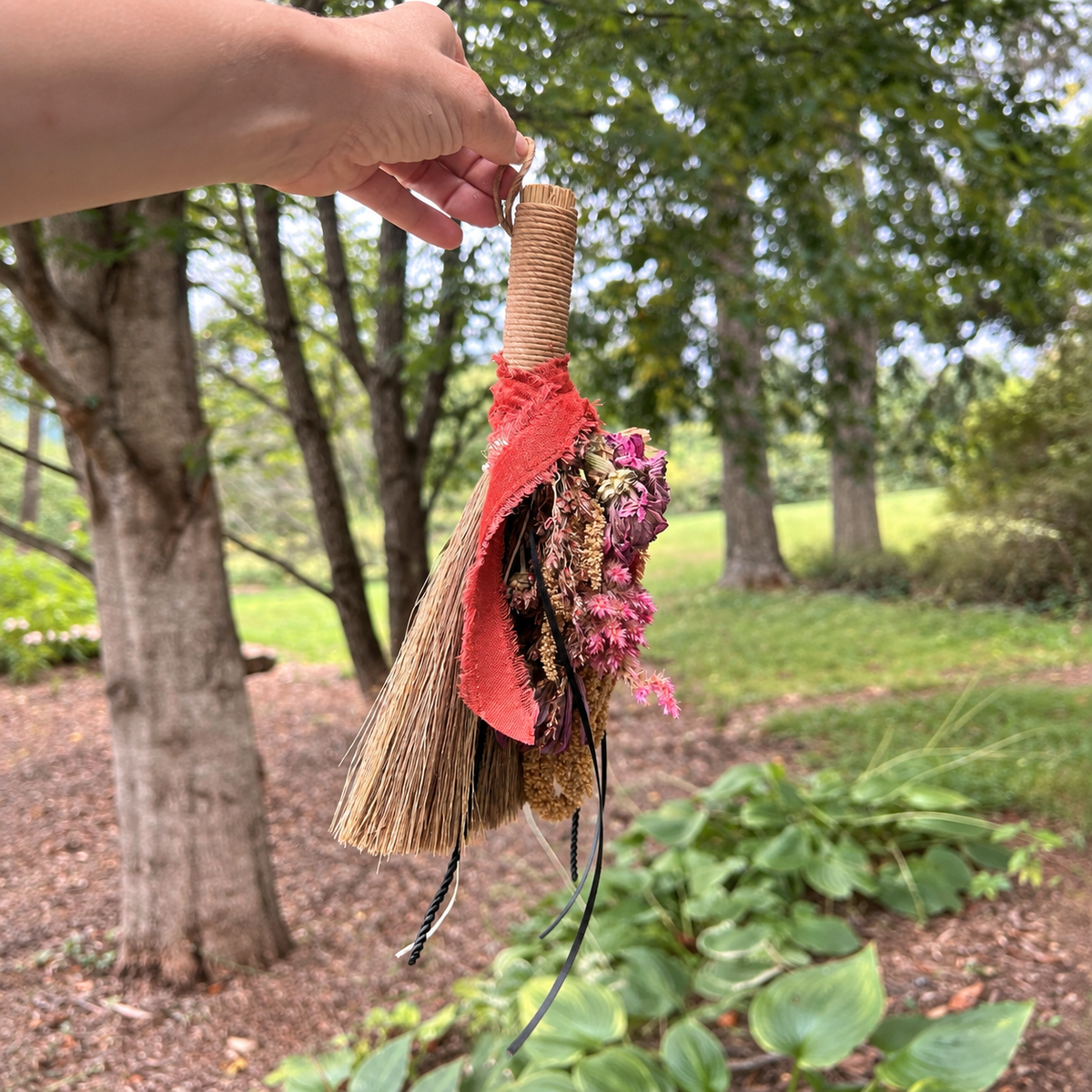 Wildheart Botanical Broom held outdoors showing its natural broomcorn, dried flowers and trailing rustic details
