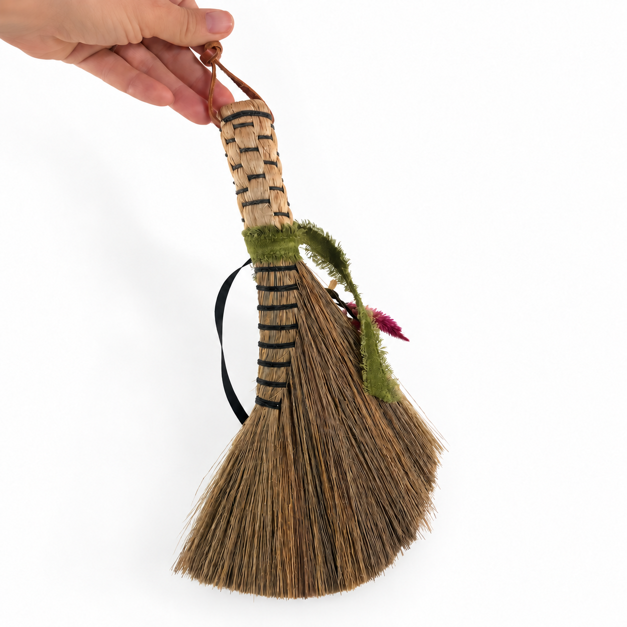 Side view of The Woodland Keeper’s Botanical Broom held by hand to show its natural bristle base, woven handle and botanical details.