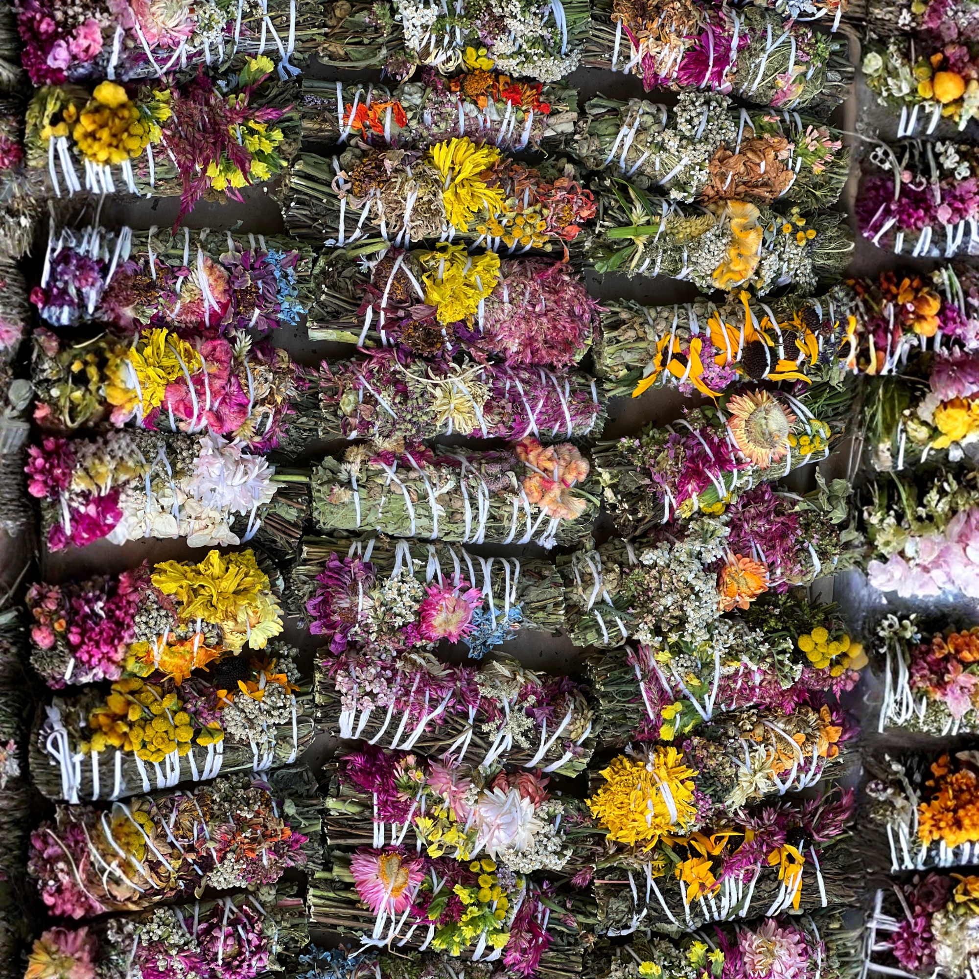 Colorful assortment of handcrafted botanical herbal wafting wands made with dried flowers and herbs