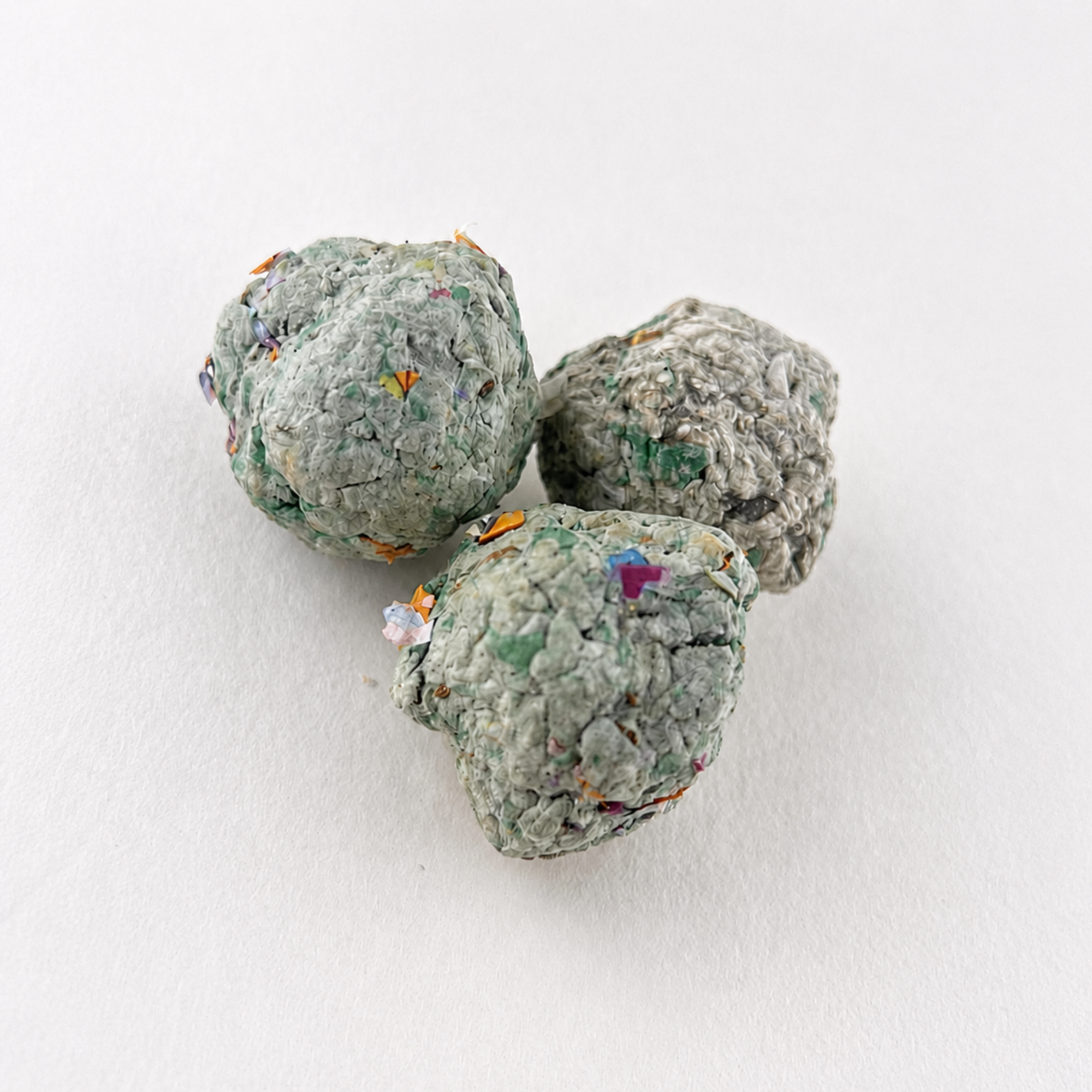 Three handmade culinary seed balls with recycled paper fibers and colorful flecks