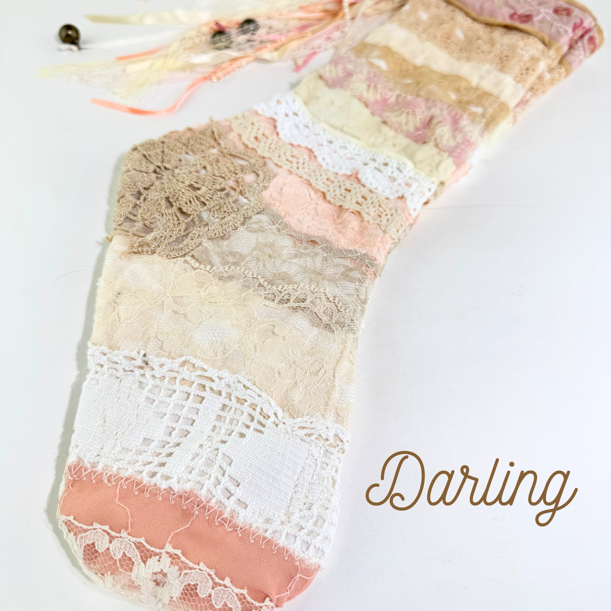 Close-up of Darling lace Christmas stocking showing crochet lace, ribbon tassels, and vintage fabric texture