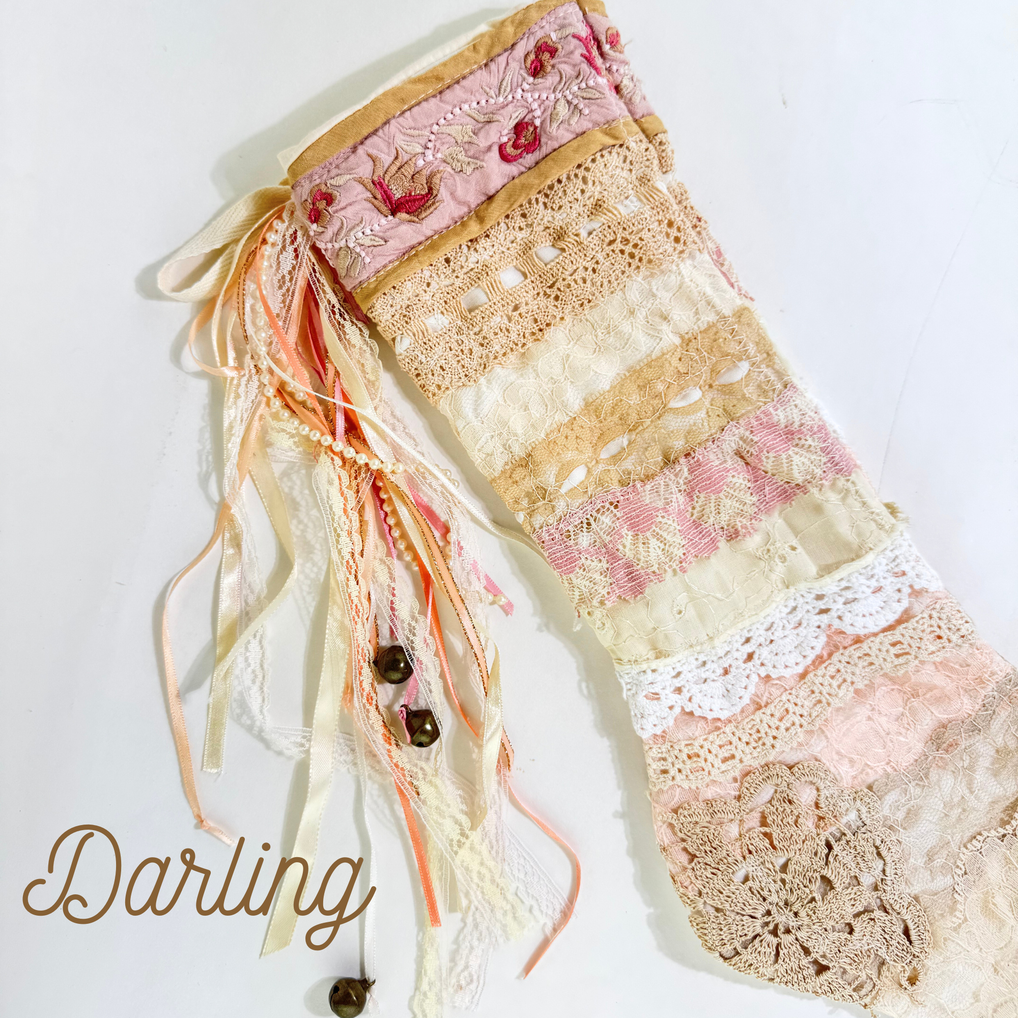 Flat lay of Darling vintage lace Christmas stocking with soft pink and cream patchwork and jingle bells