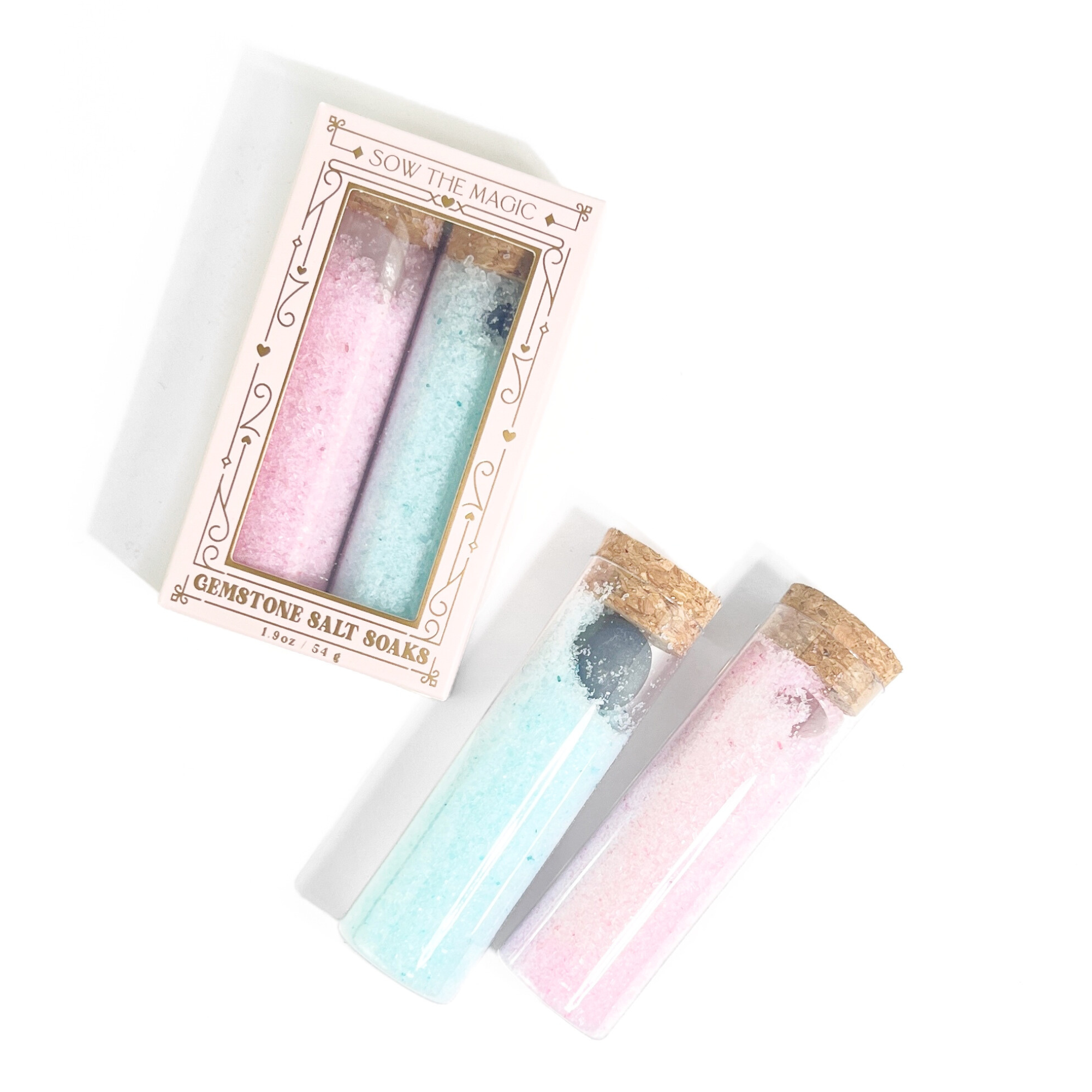Open salt soak set showing two vials of pink and blue salts with gemstones and cork lids on white background
