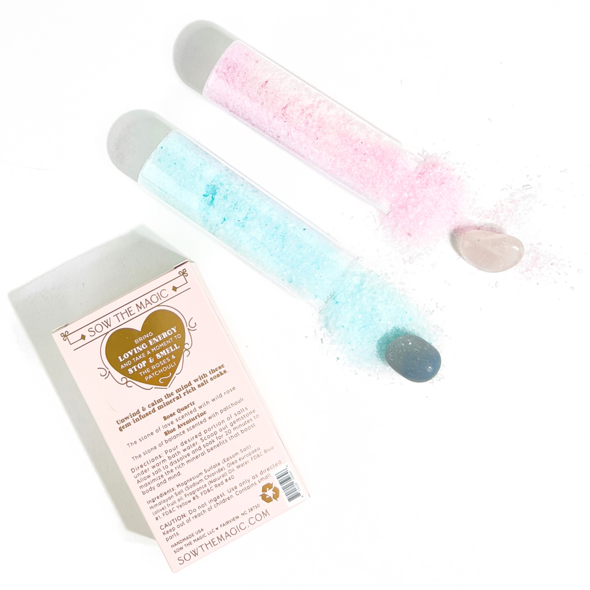 Flatlay of blue and pink bath salt vials with gemstones beside Sow the Magic packaging