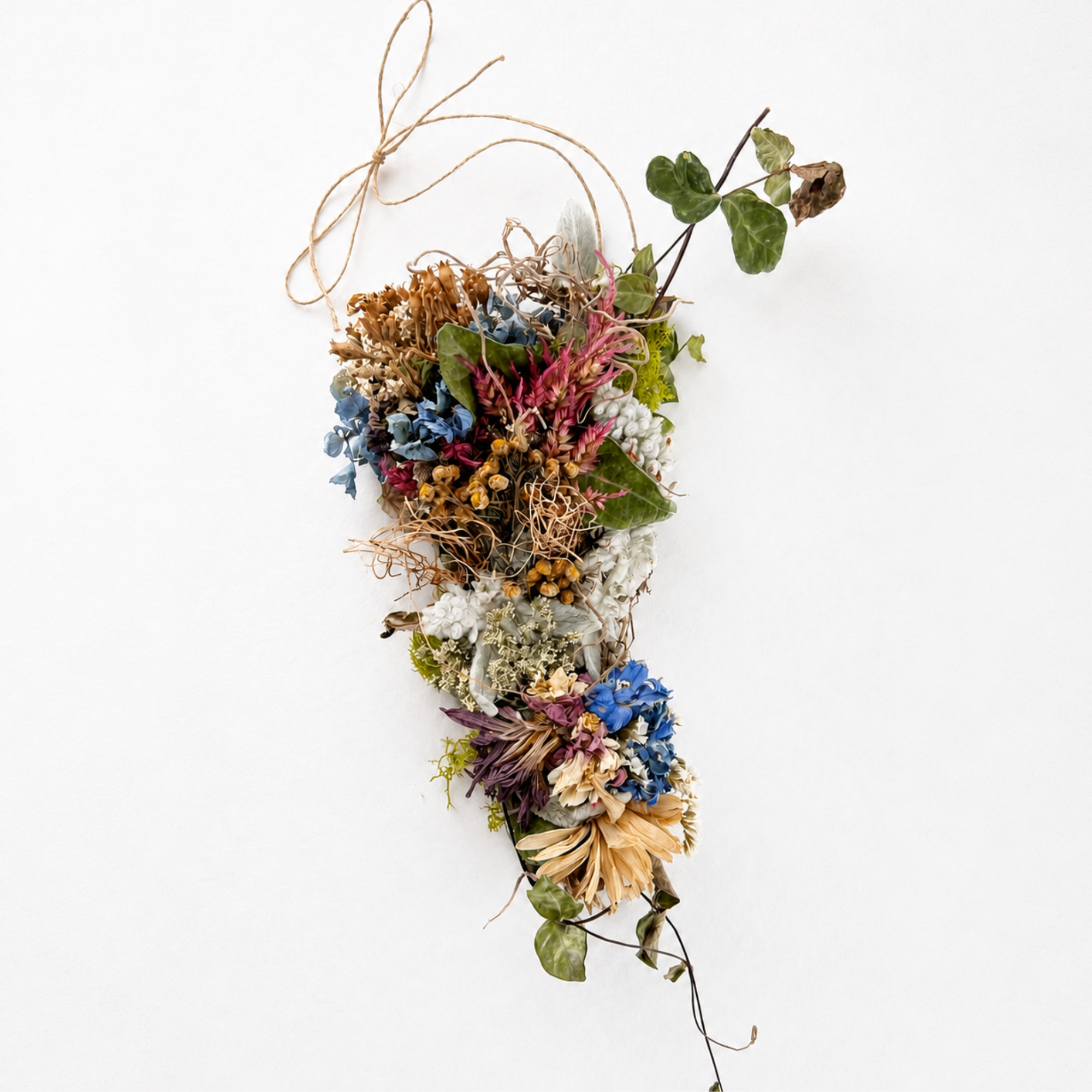 Handmade botanical wall hanging featuring dried flowers, moss, leaves and natural twine on a white background