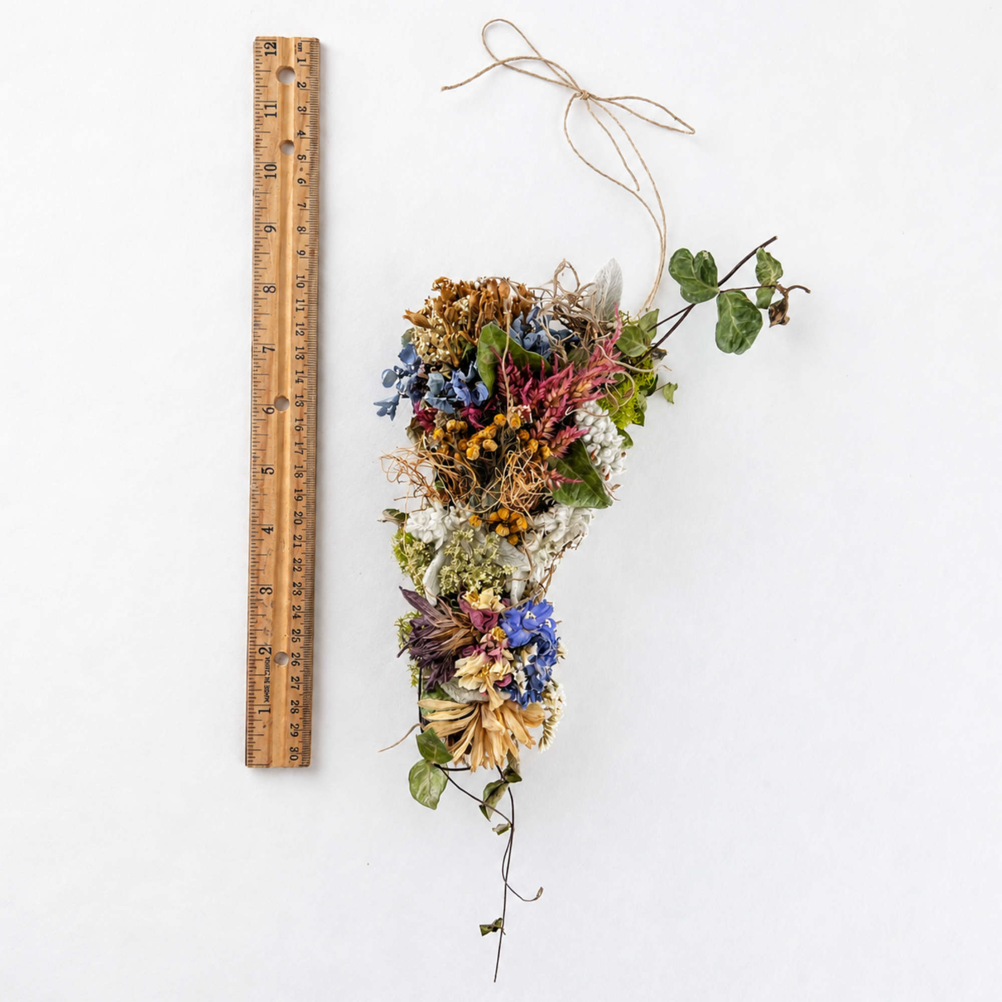 Handmade dried botanical wall hanging displayed beside a wooden ruler to show its length