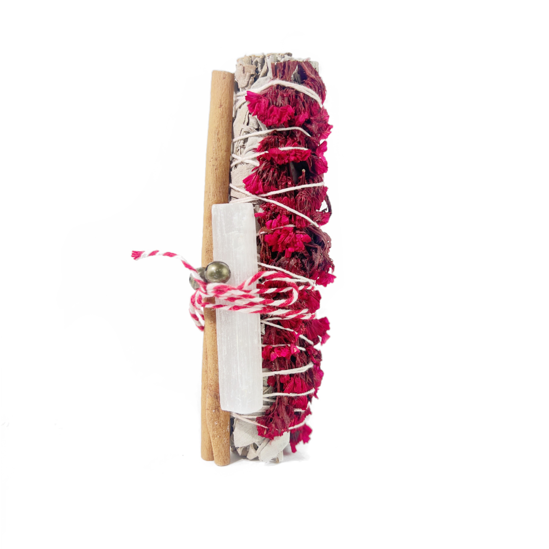 Close-up of red sinuata and white sage smudge bundle tied with red and white twine