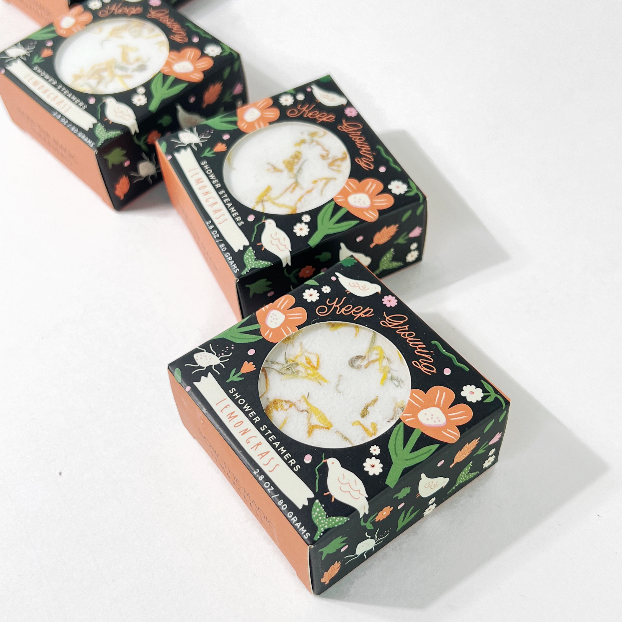 Three Keep Growing lemongrass shower steamers in floral packaging by Sow the Magic
