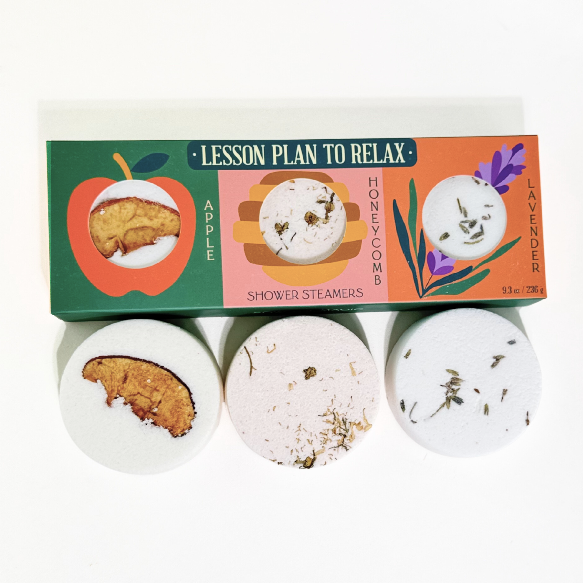 Lesson Plan to Relax Shower Steamers trio displayed with packaging and three round steamers showing apple, honeycomb, and lavender botanicals