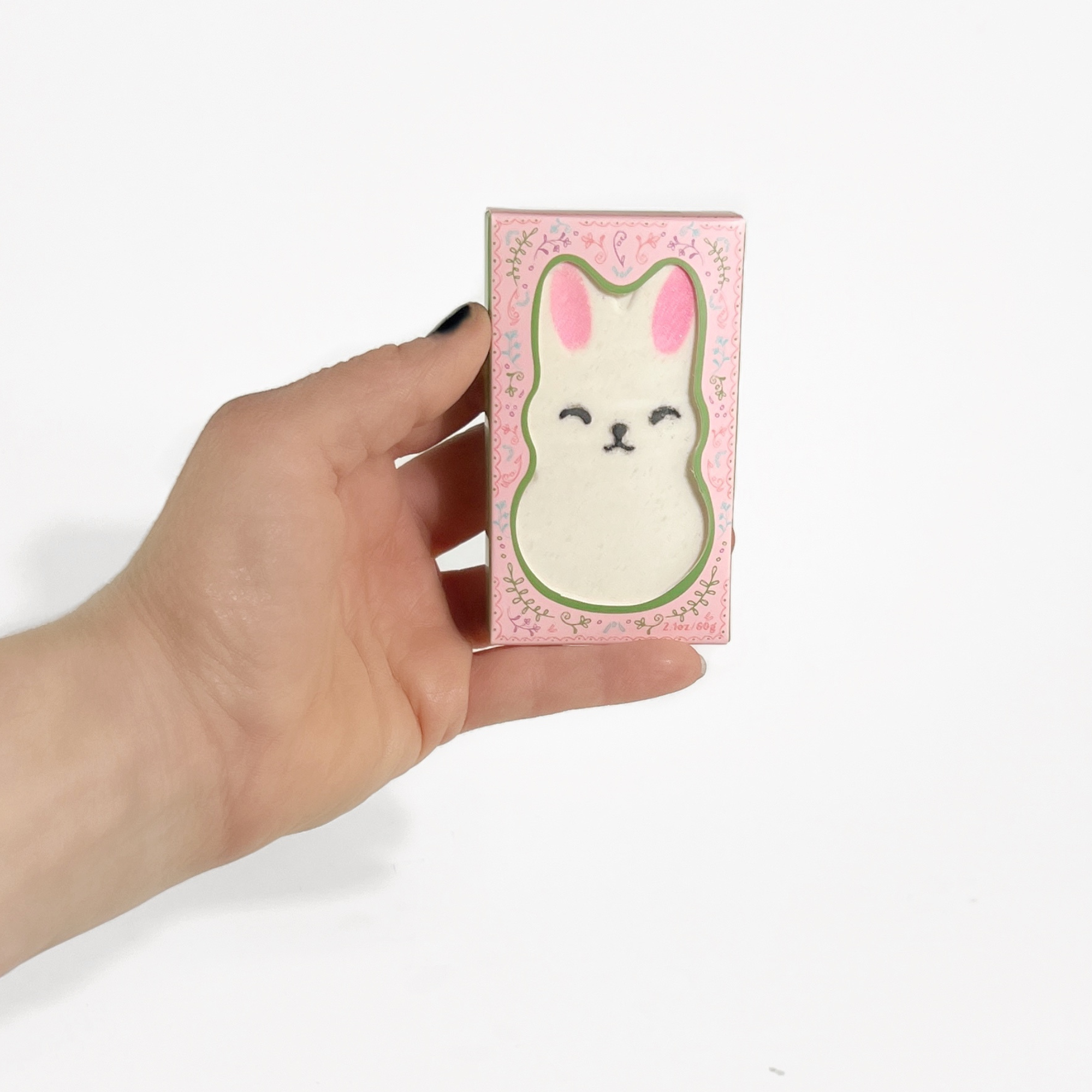 Hand holding boxed Little Bunny Strawberry Bath Bomb with pink and green design