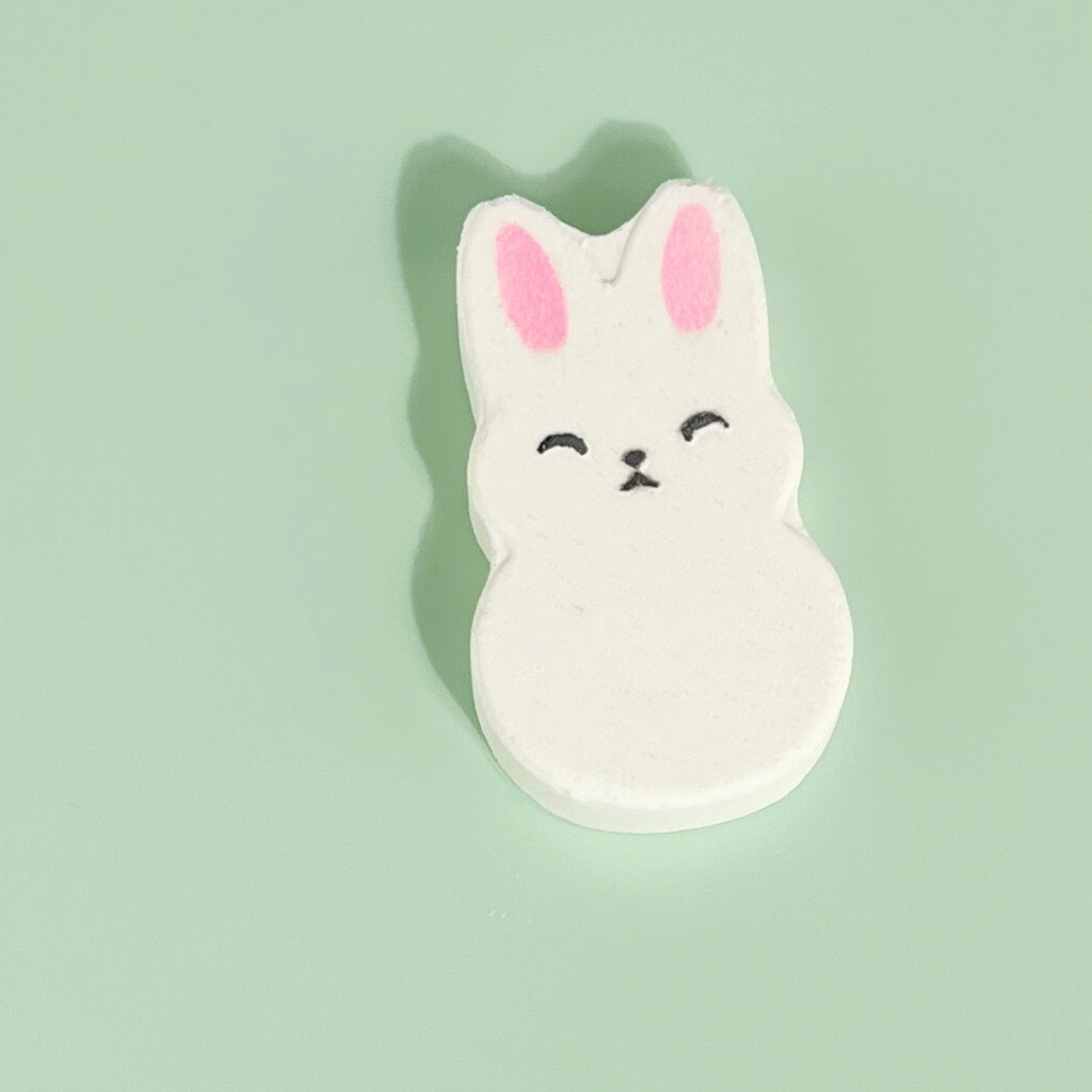 Single bunny-shaped strawberry bath bomb with pink ears on light green background