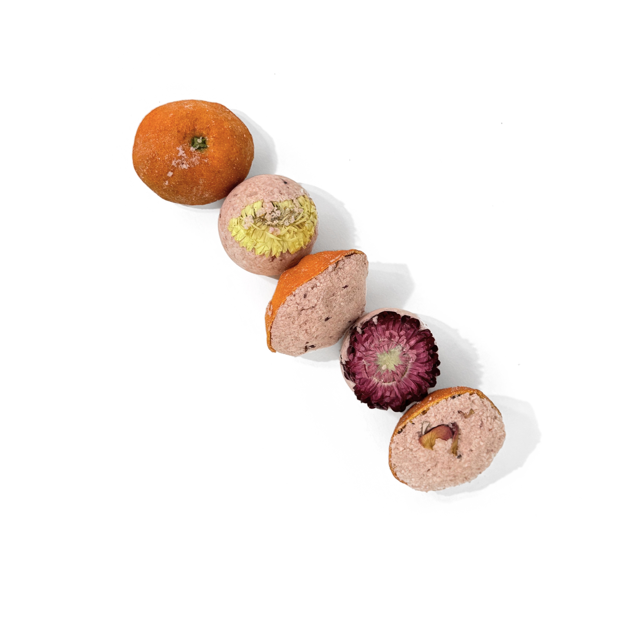 Lineup of Mandarin Scoops bath bombs displaying real mandarin peel and flower tops on white background