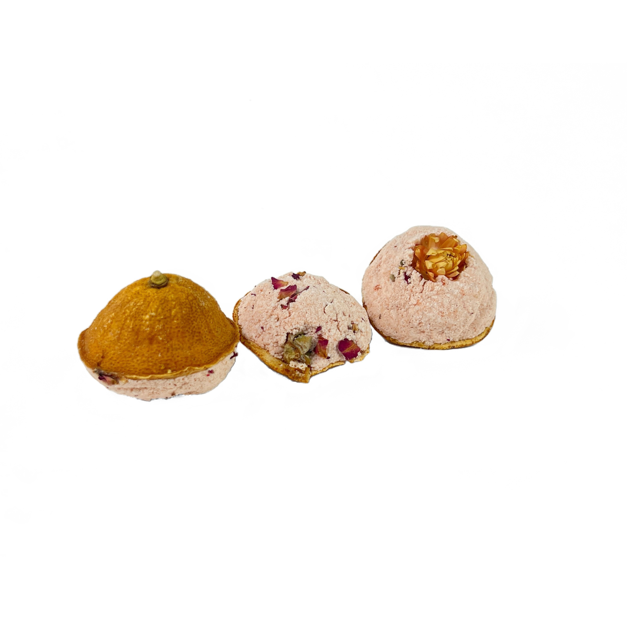 Close-up of three Mandarin Scoops bath bombs featuring dried citrus peel and floral botanicals