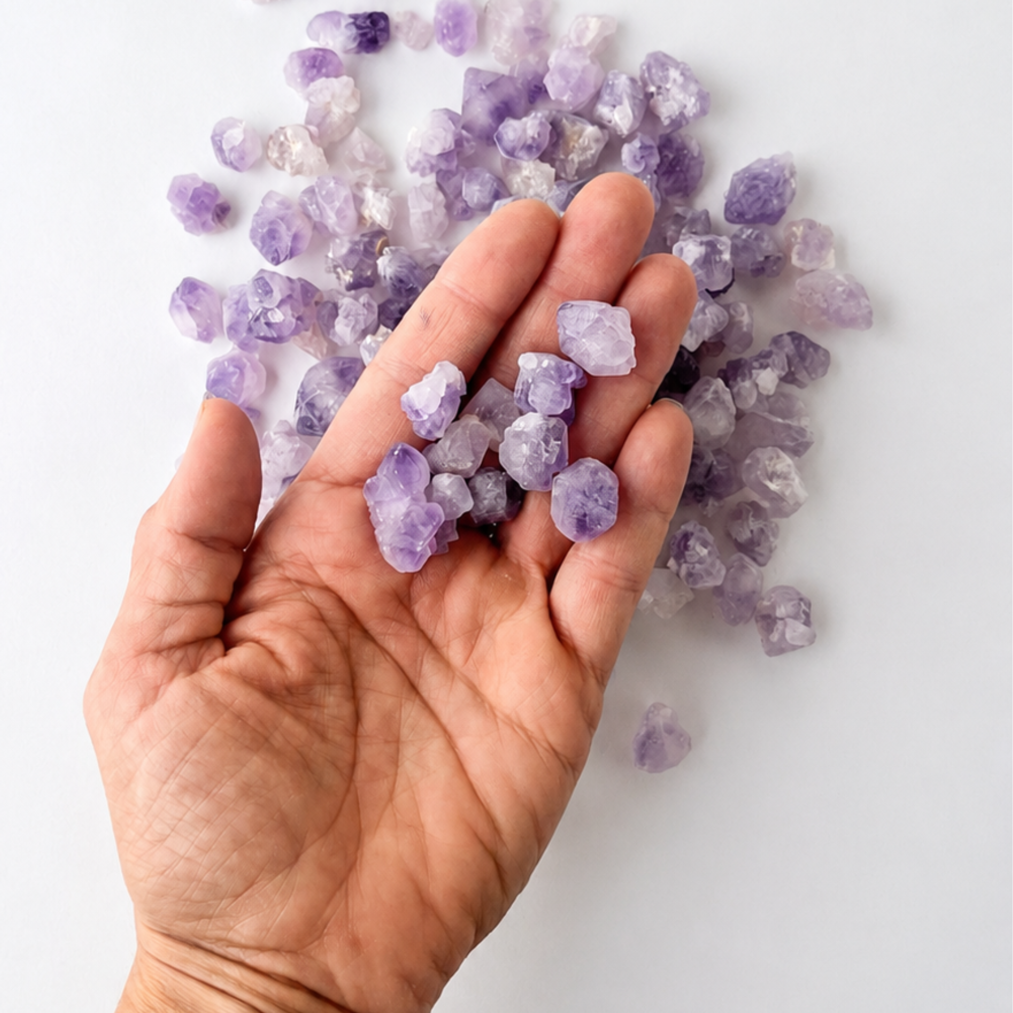 Mini Brazilian amethyst crystal points held in a hand to show their small size and raw texture