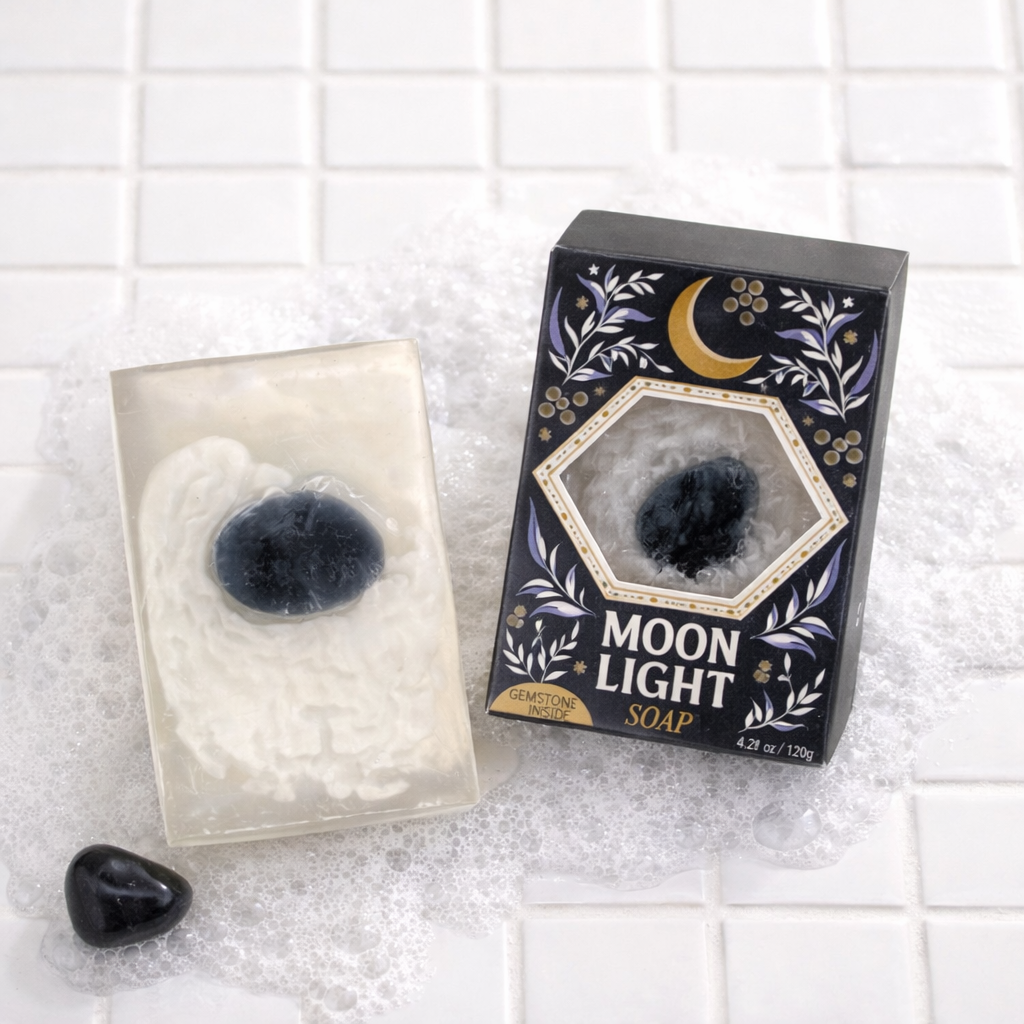 Moon Light gemstone soap with obsidian stone beside box packaging on white tile floor with soap suds and tumbled obsidian crystal