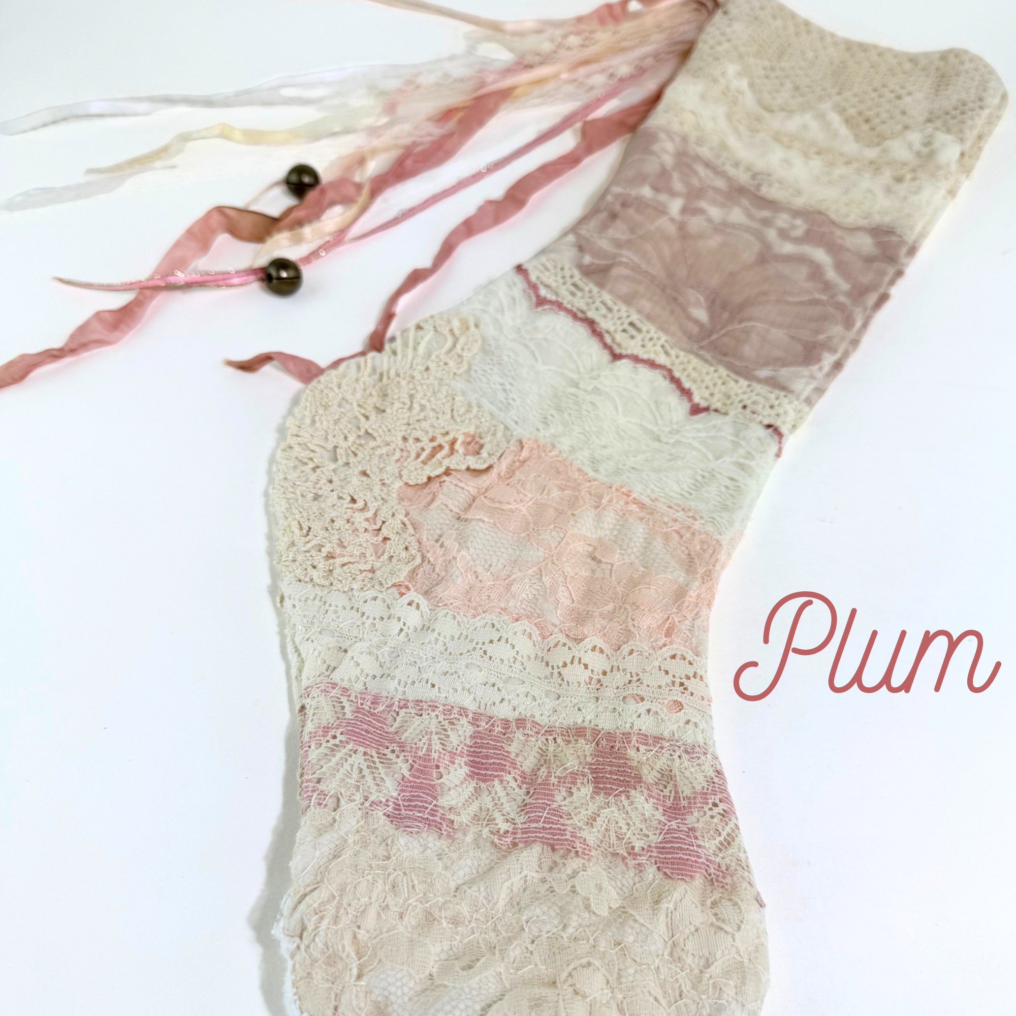 Close-up of Plum lace Christmas stocking showing pastel lace layers and pink ribbon tassel accents