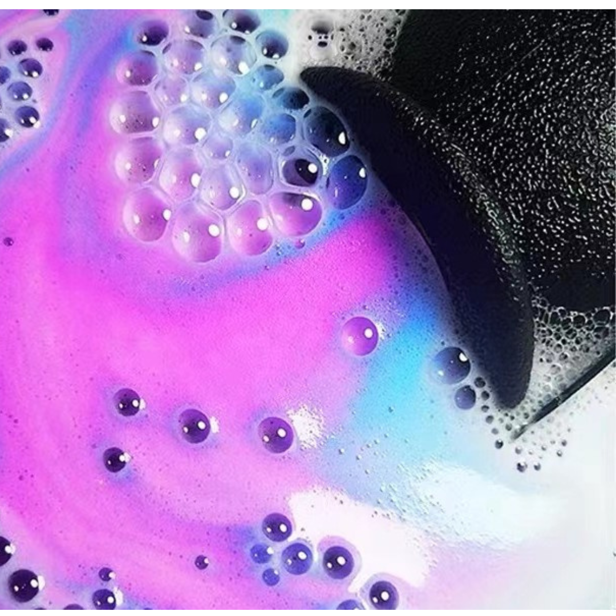 Close-up of rainbow cauldron bath bomb fizzing in water with colorful purple, pink, and blue bubbles