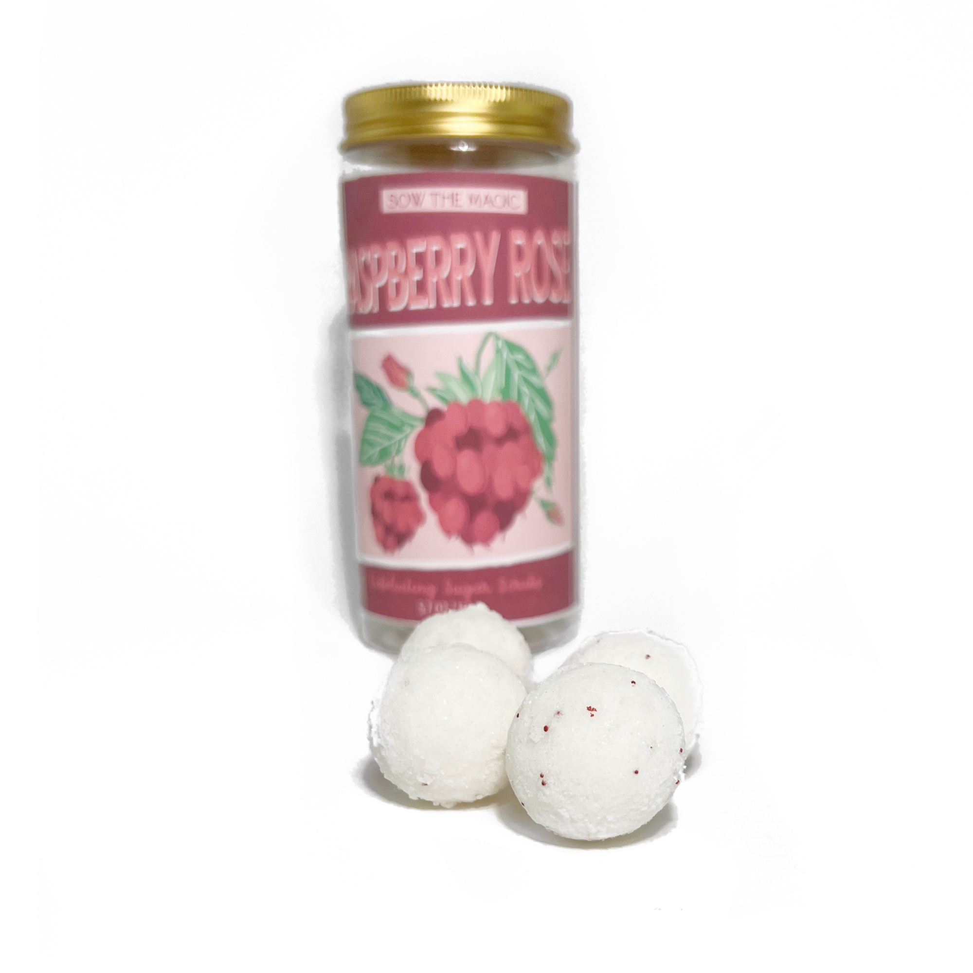 Flat lay of Raspberry Rose sugar scrub balls spilling from open jar