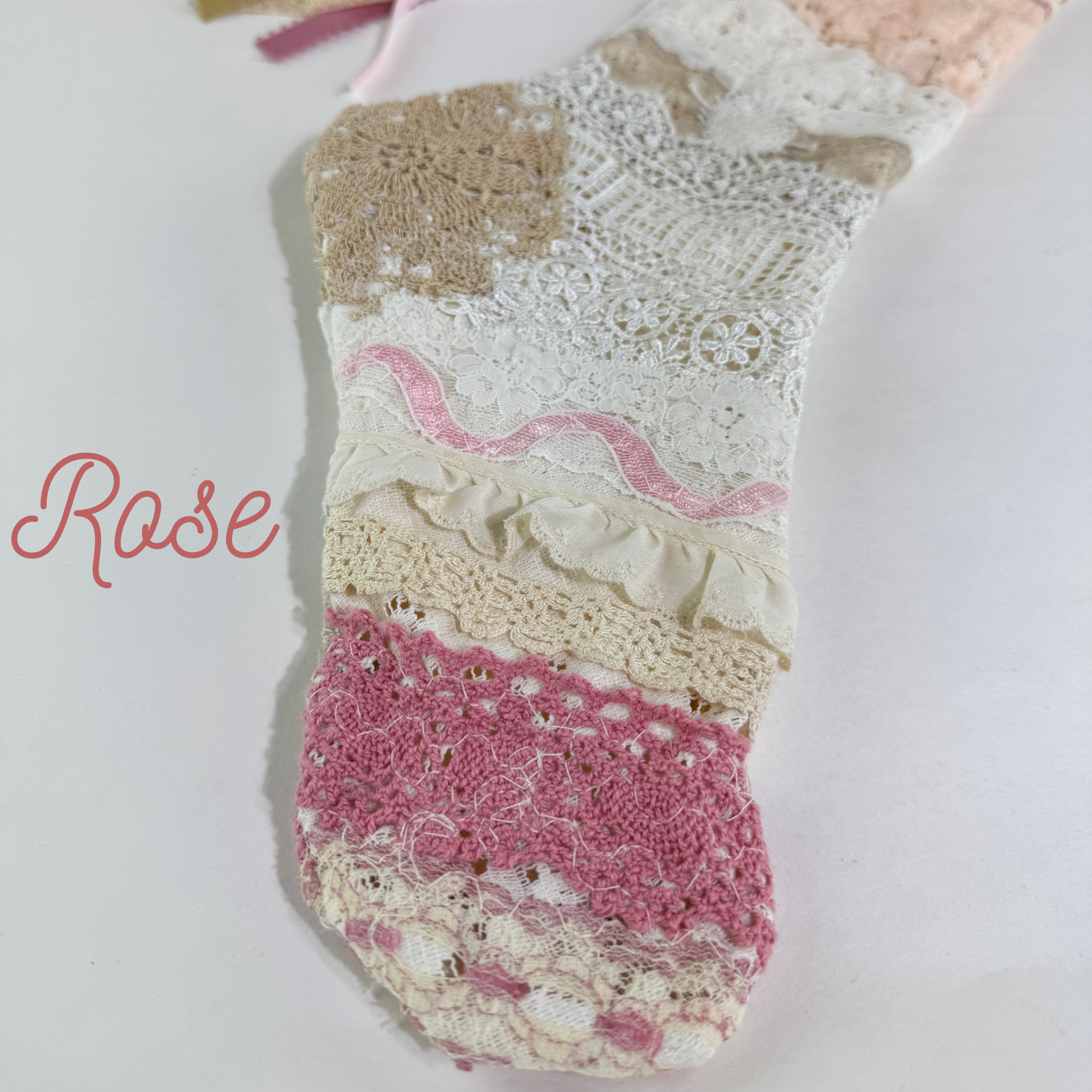 Close-up of stocking toe showing pink lace layers, crochet trim, and soft blush vintage fabrics