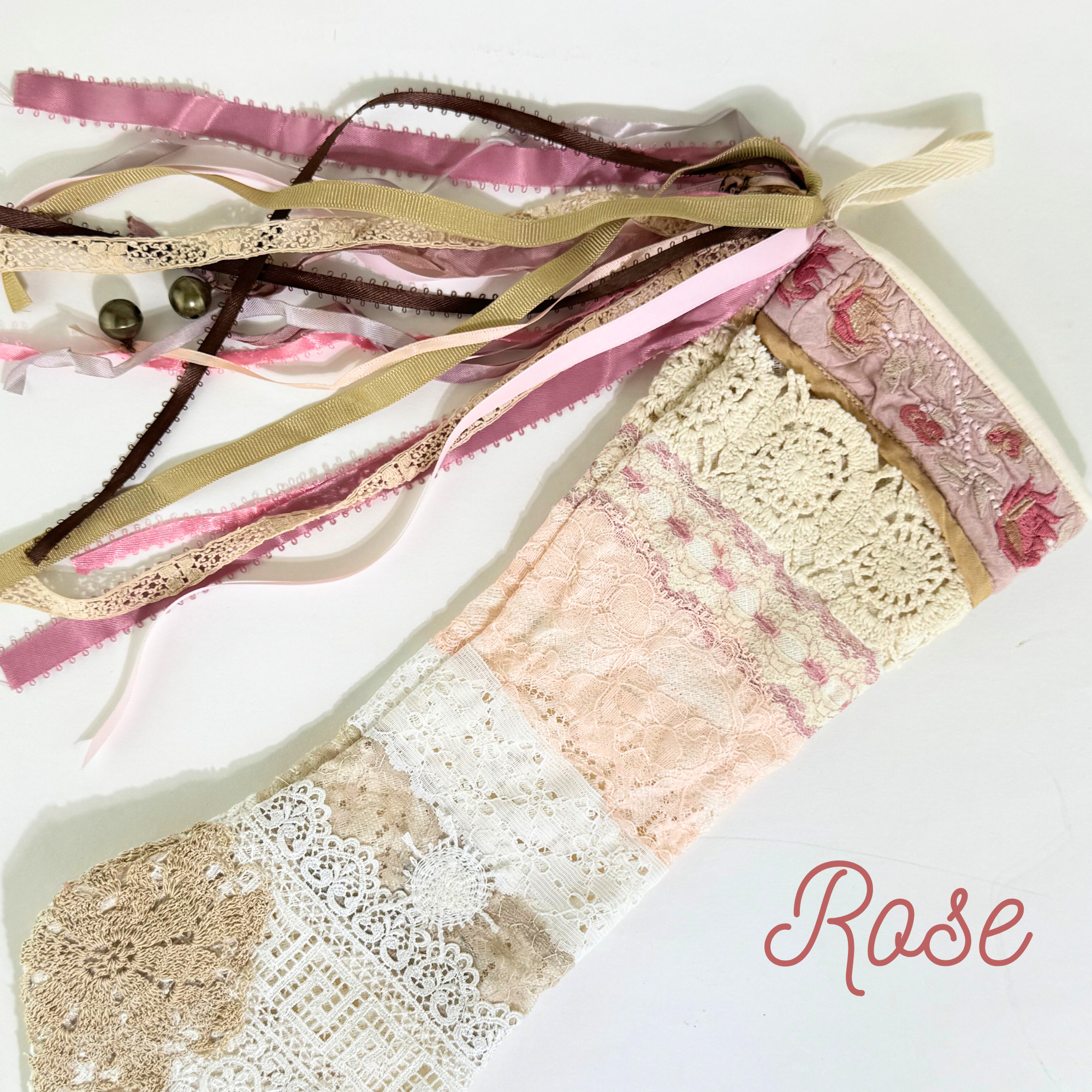 Flat lay of Rose handmade lace Christmas stocking with mauve ribbons and vintage crochet lace details