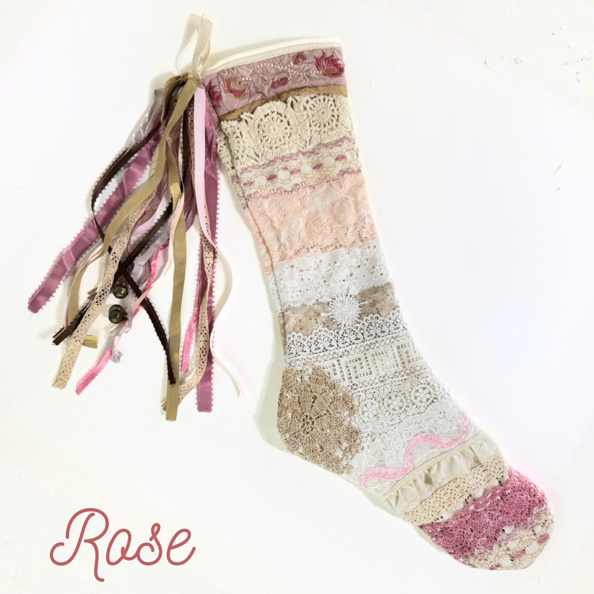 Rose lace Christmas stocking with pink, cream, and tan patchwork lace design and cascading ribbon tassels