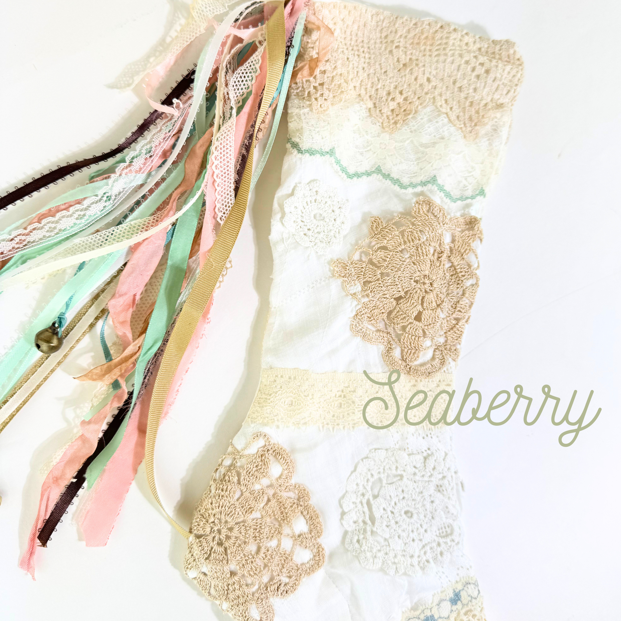 Flat lay of Seaberry handmade lace Christmas stocking with mint and peach ribbons and neutral patchwork