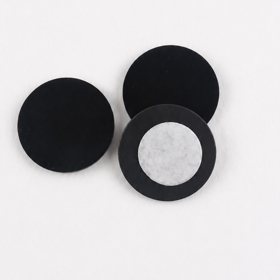 Three round black Shungite stone stickers showing smooth tops and adhesive backing
