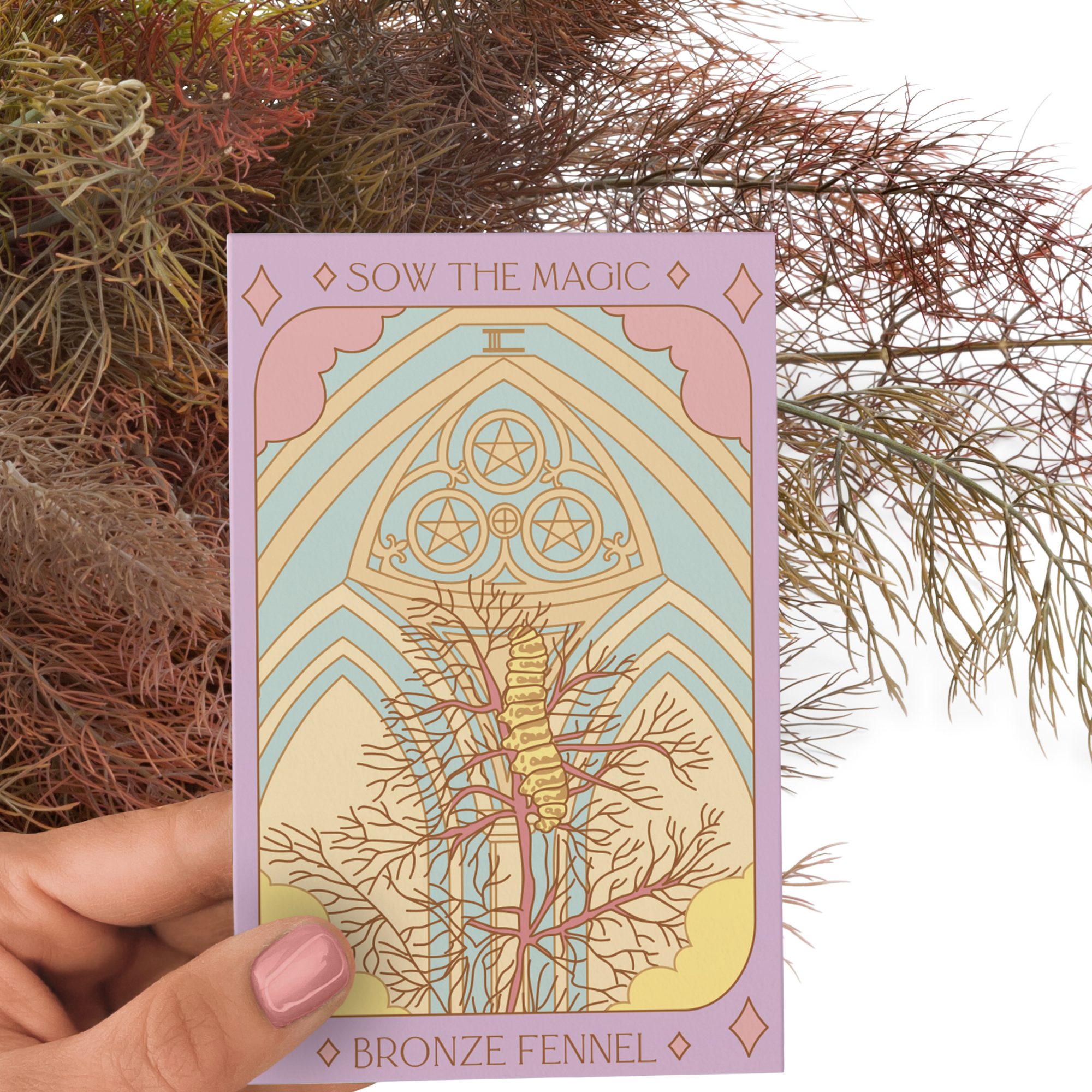Bronze Fennel tarot seed packet held by hand showing pastel artwork with herbal background