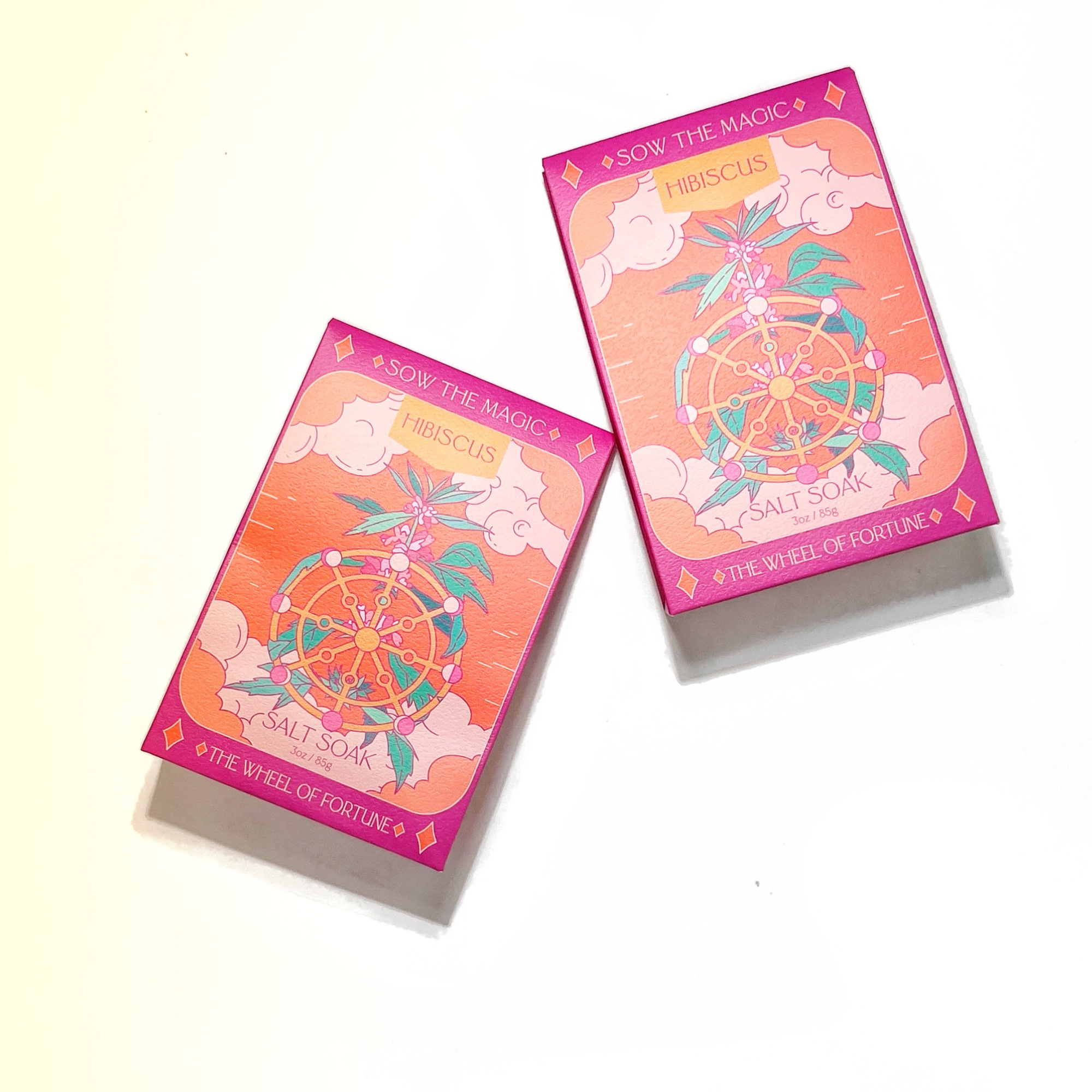 Two Wheel of Fortune Hibiscus Salt Soak boxes with pink and coral tarot card design on white background