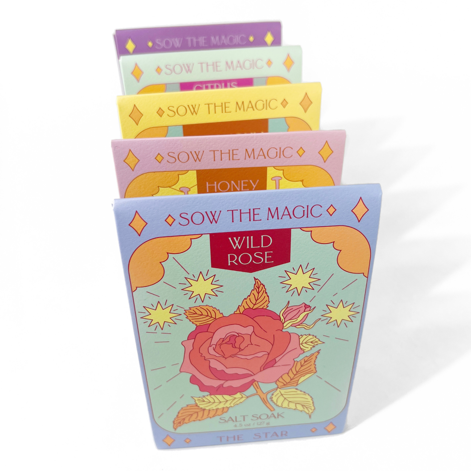 Row of colorful Sow the Magic tarot-inspired salt soaks featuring Wild Rose, Honey, Citrus, Lavender, and Patchouli