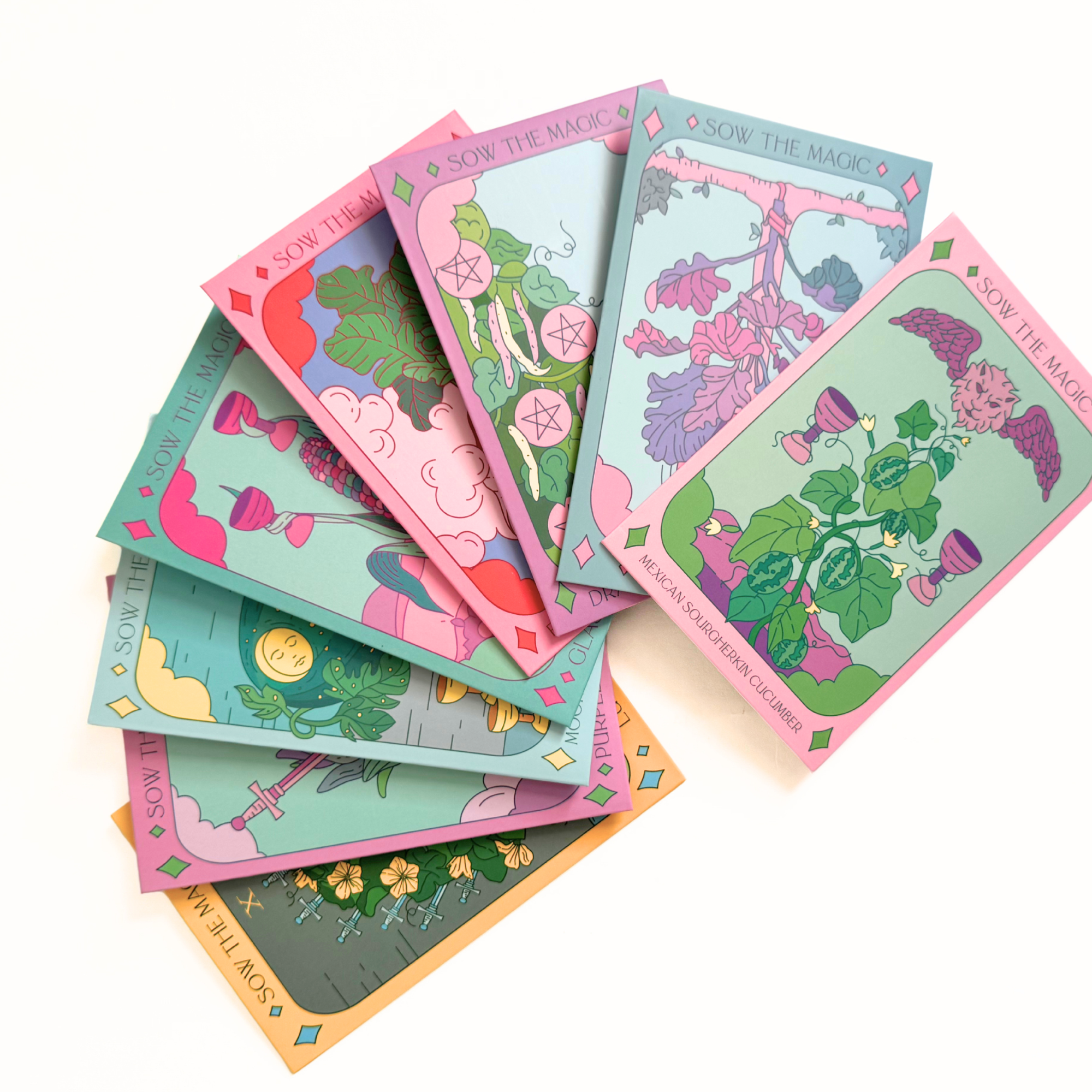 Fan of colorful Sow the Magic tarot seed packets featuring vegetable illustrations on white background