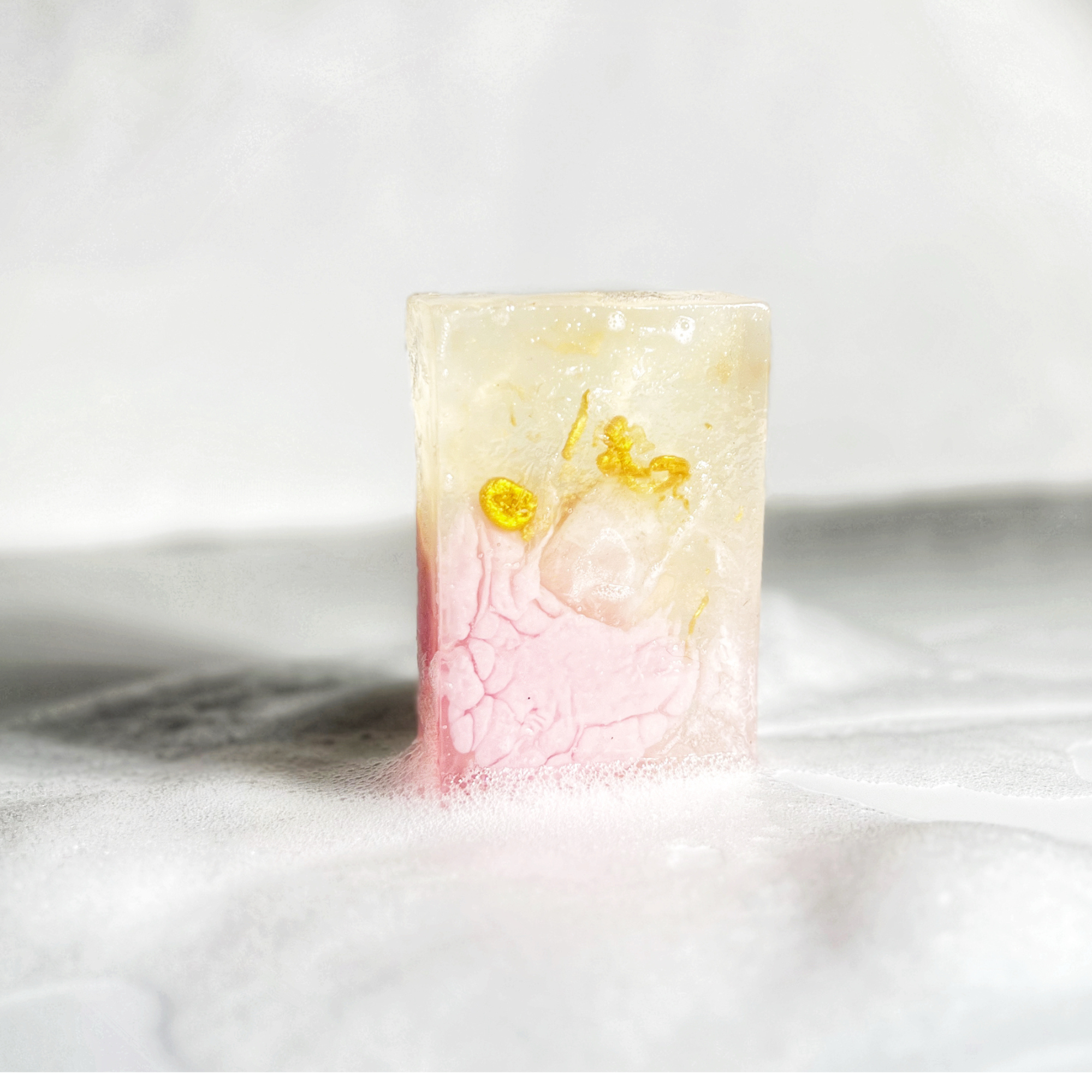 Spirited Sunset Gemstone Soap in use with gentle bubbles highlighting pink rose tone and gemstone detail.